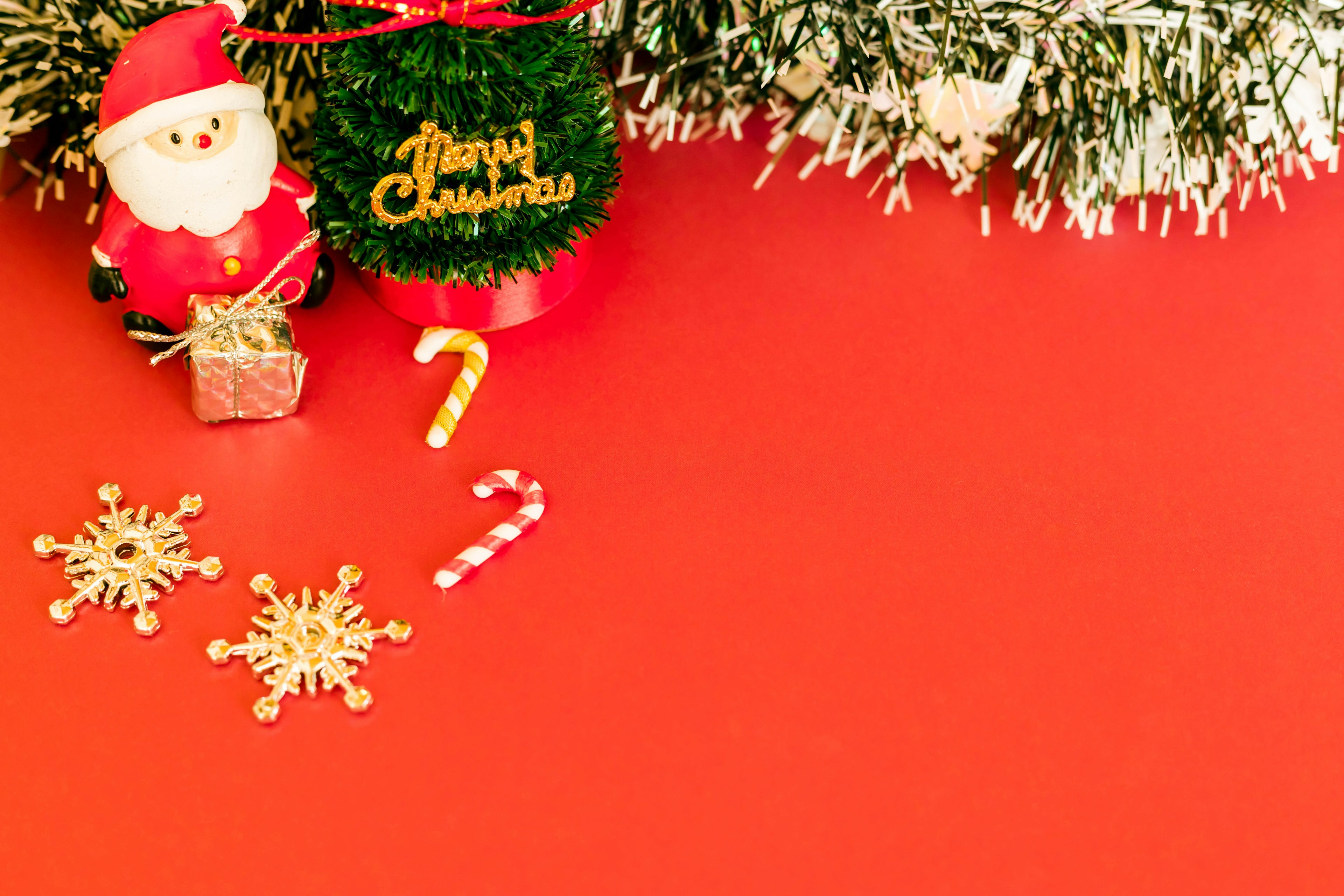 A festive scene with a Santa figurine and Christmas decorations on a red background