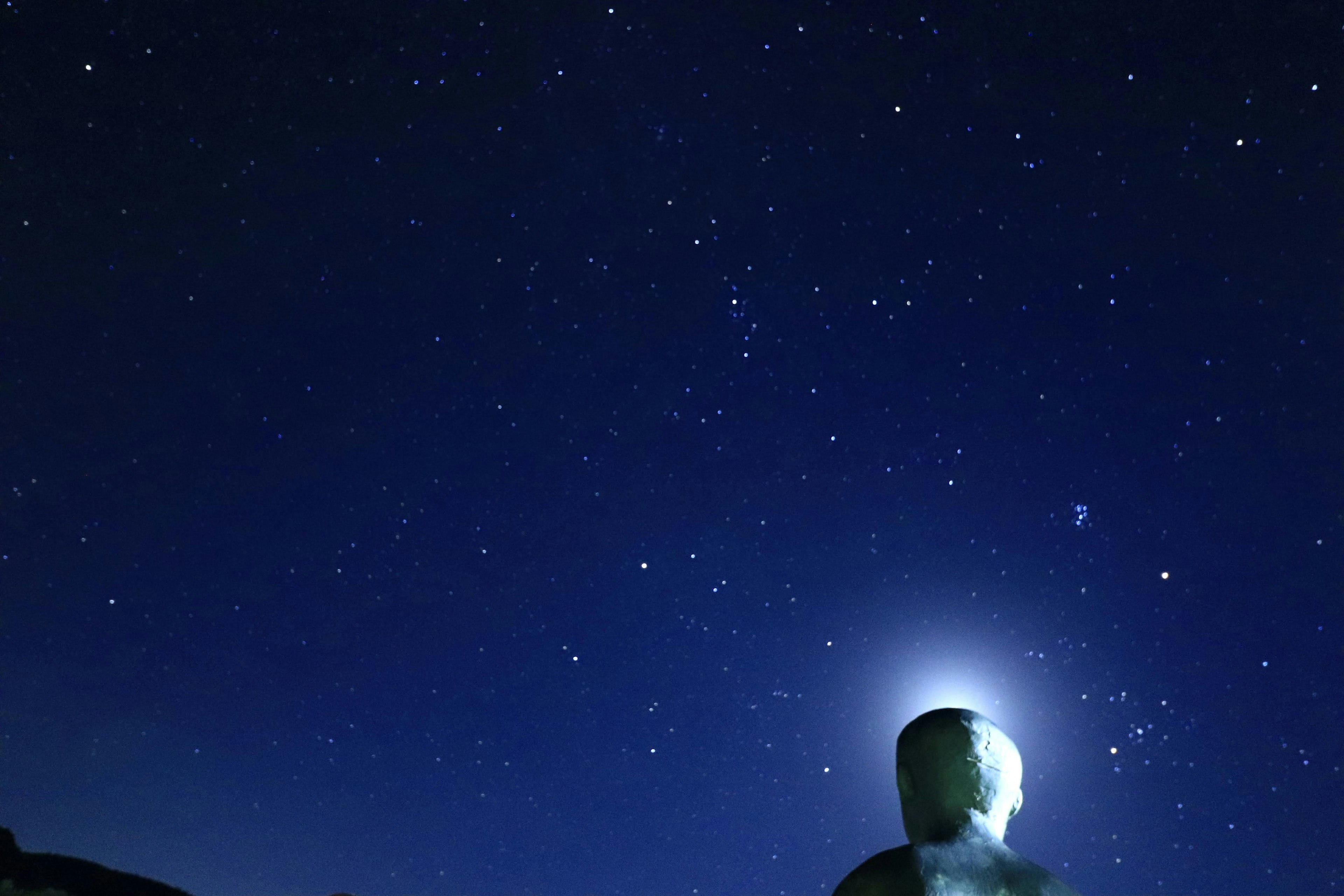 Silhouette seorang di bawah langit berbintang diterangi oleh cahaya bintang