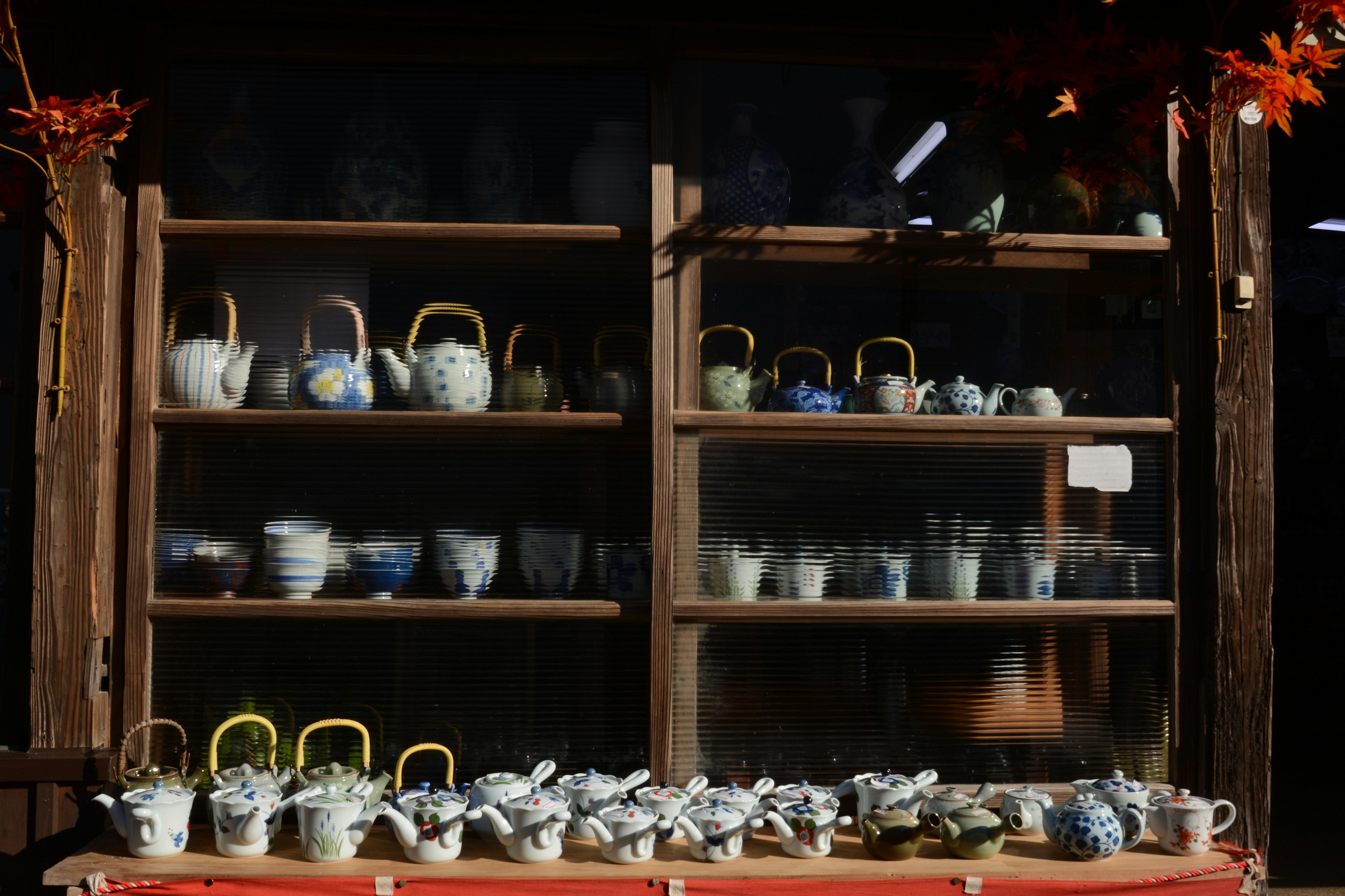 Collection of teapots and cups displayed on wooden shelves