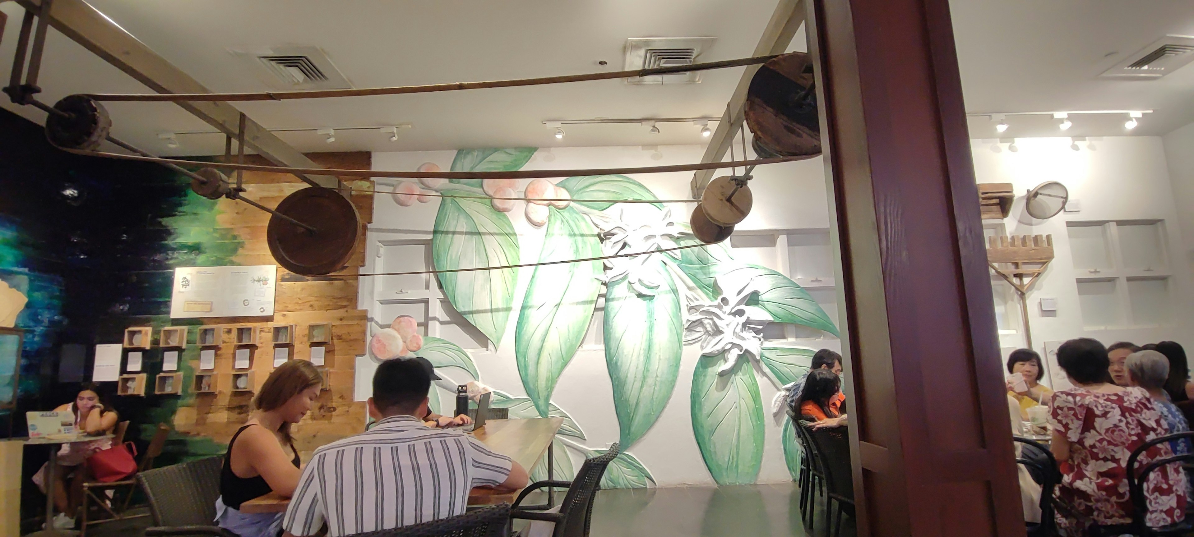 Interior of a cafe featuring a green mural and patrons