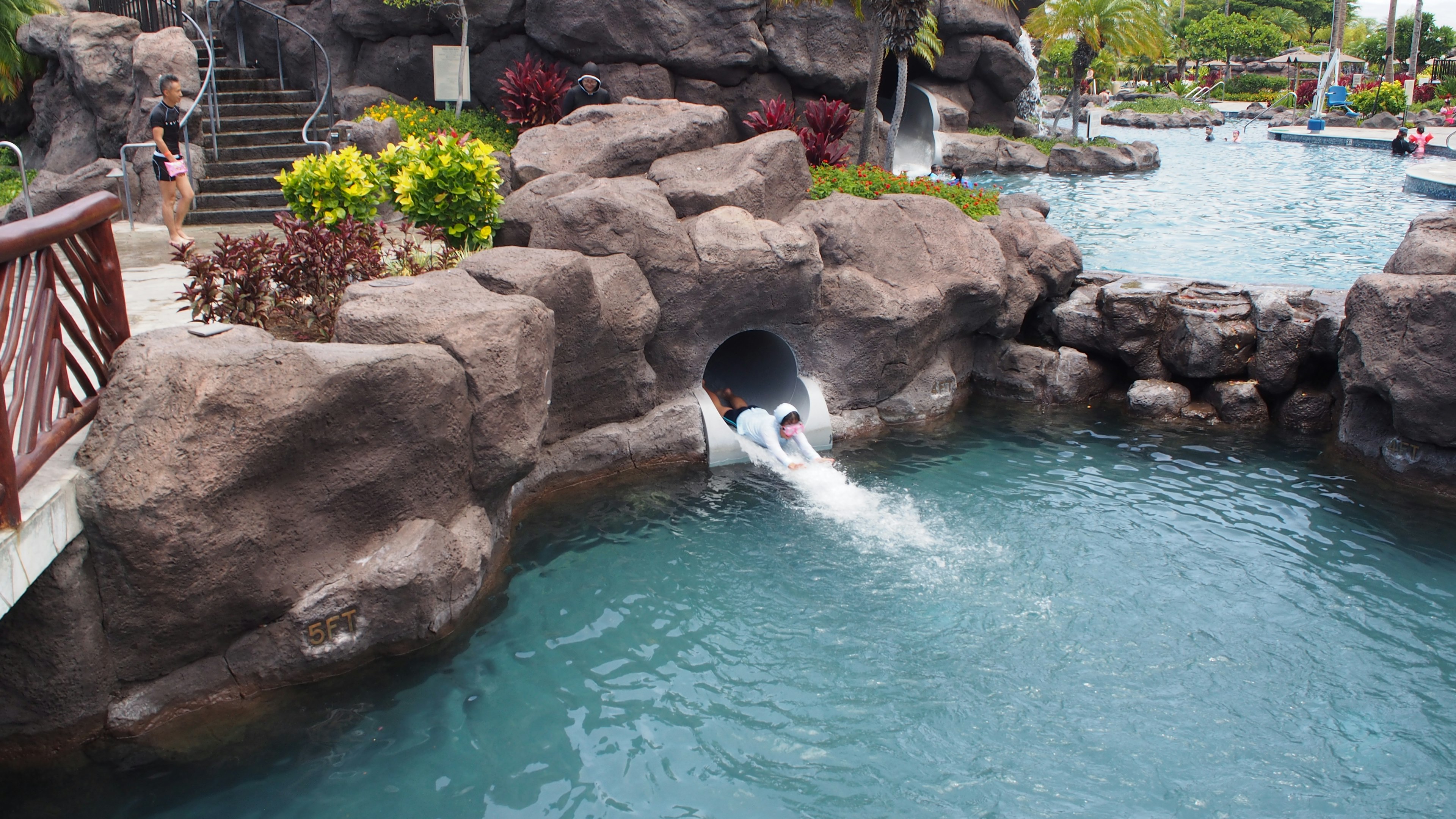 Kind rutscht von einer Wasserrutsche in einen Pool