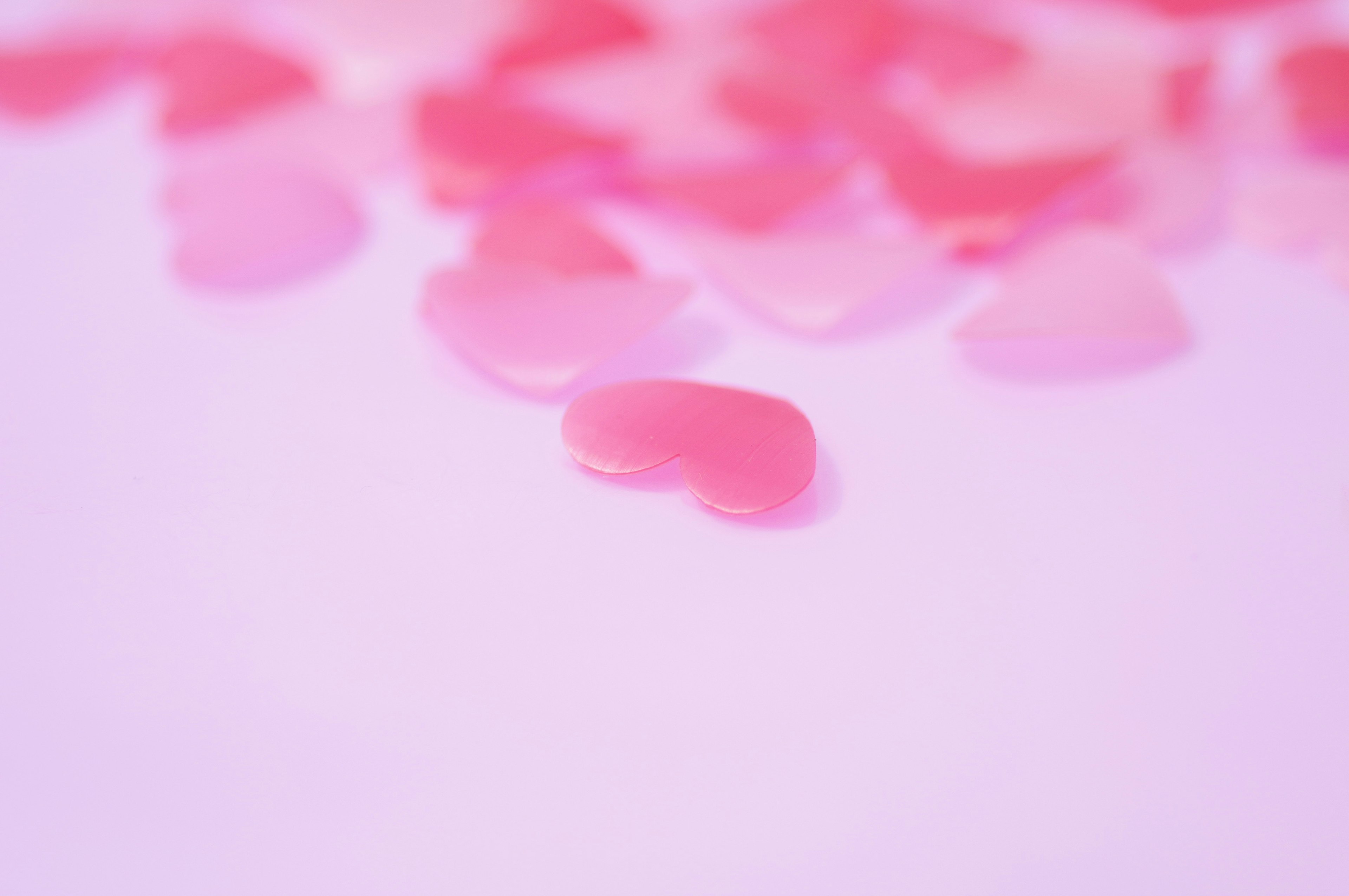 Scattered pink heart-shaped decorations on a soft background