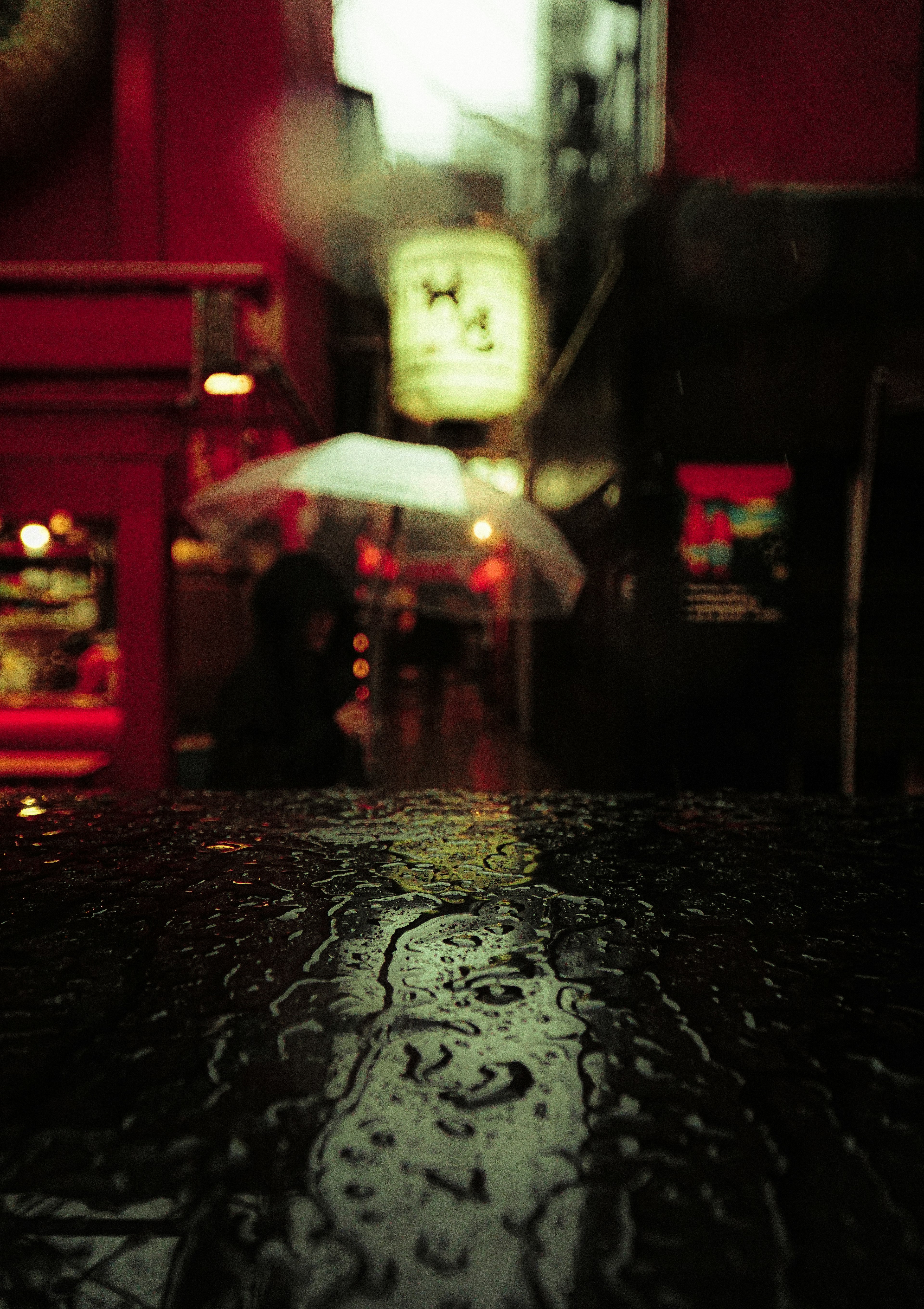 Street scene with reflections on a wet wooden table and an umbrella