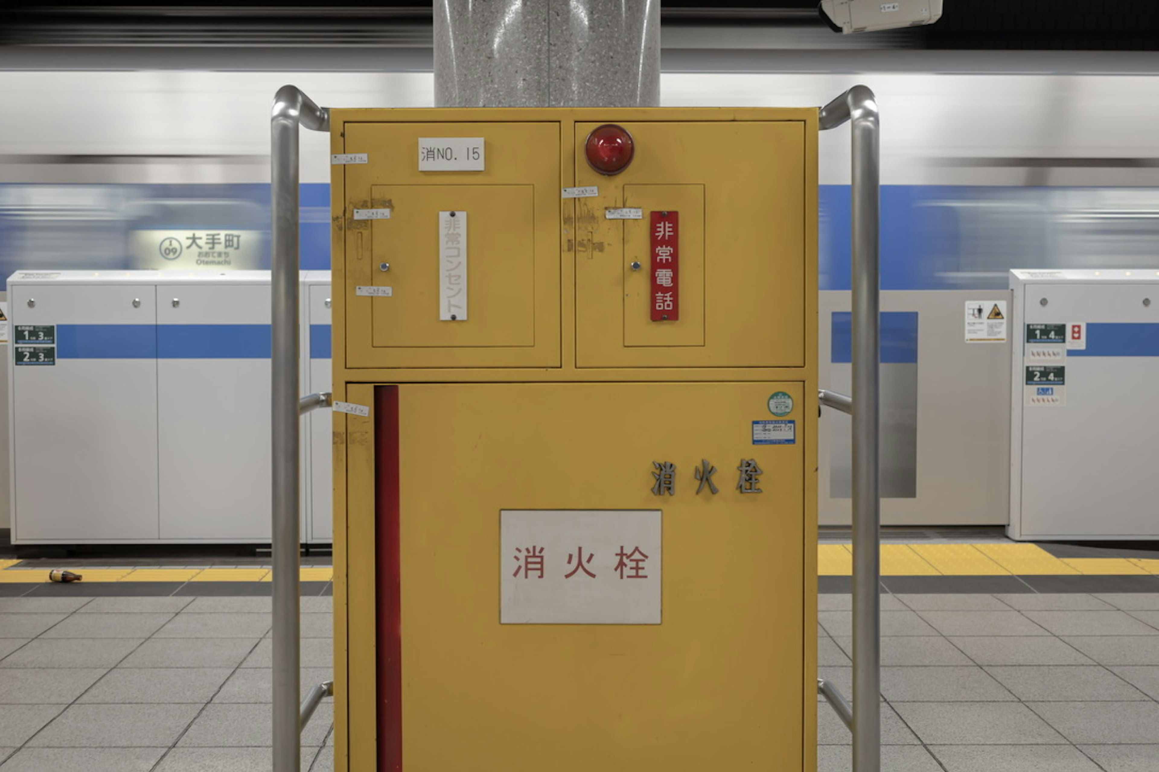 Yellow fire extinguisher at a subway station with surrounding structures