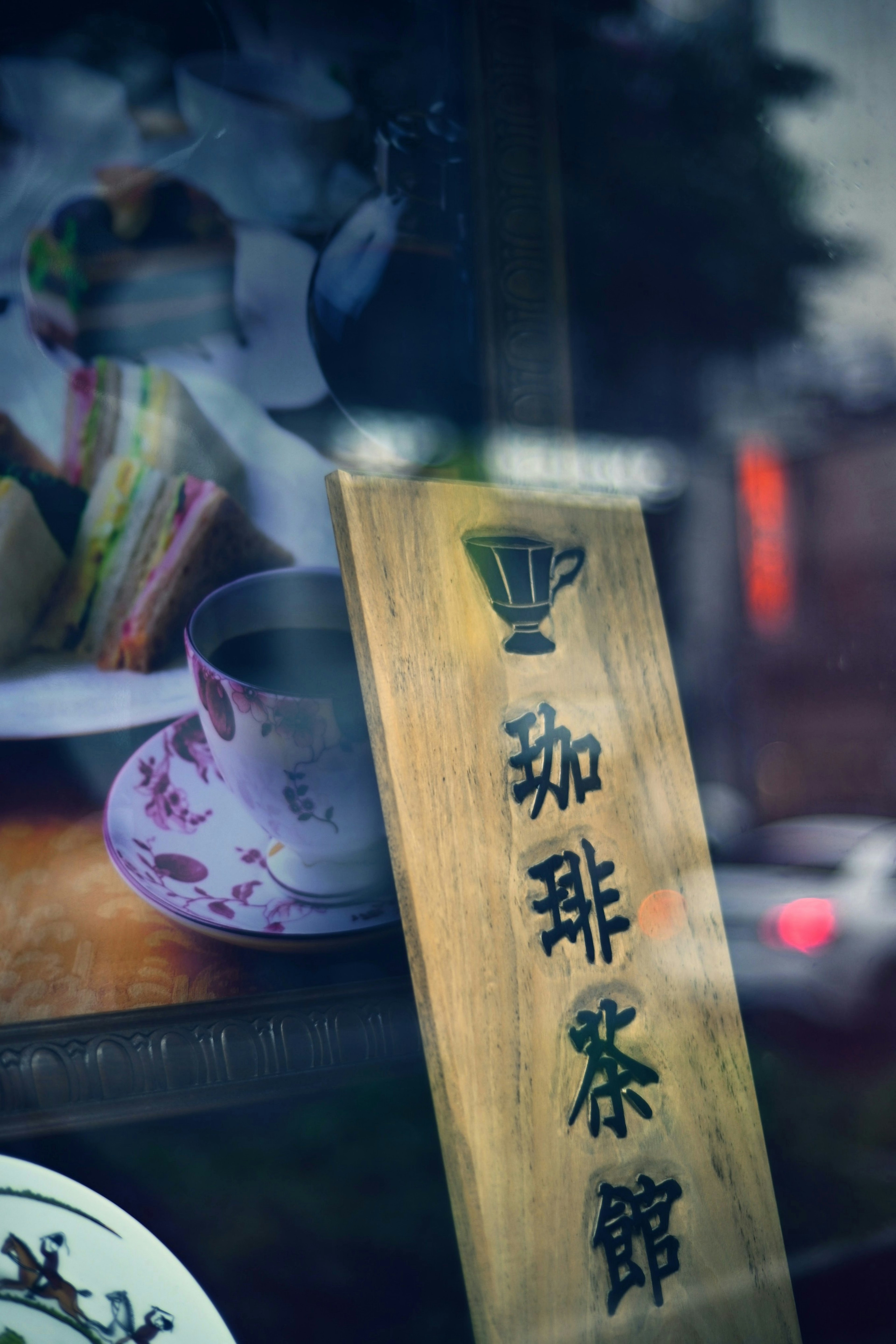 Panneau de café avec des caractères japonais et une tasse de thé reflétée dans la fenêtre