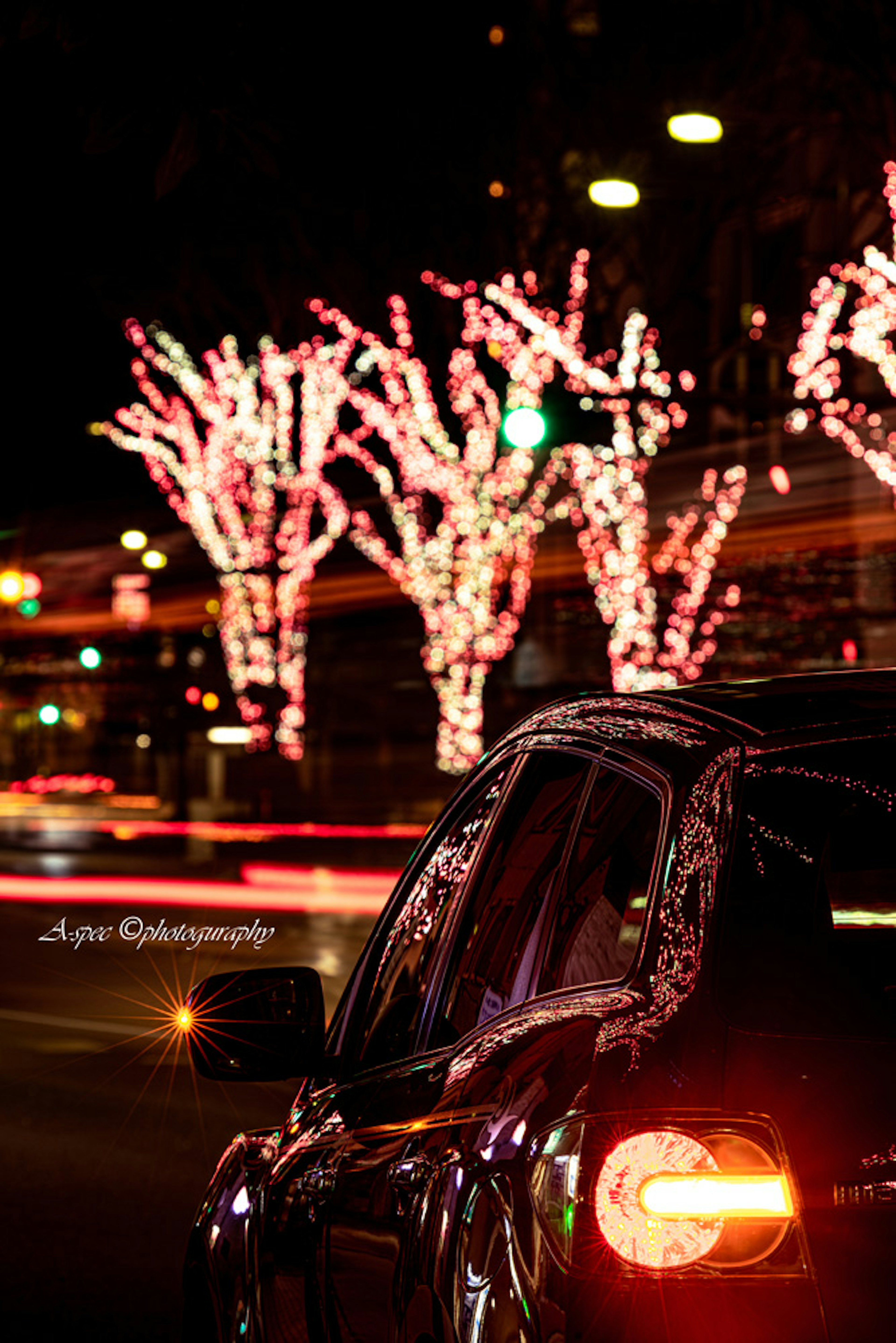 Voiture noire garée la nuit avec des lumières roses sur des arbres