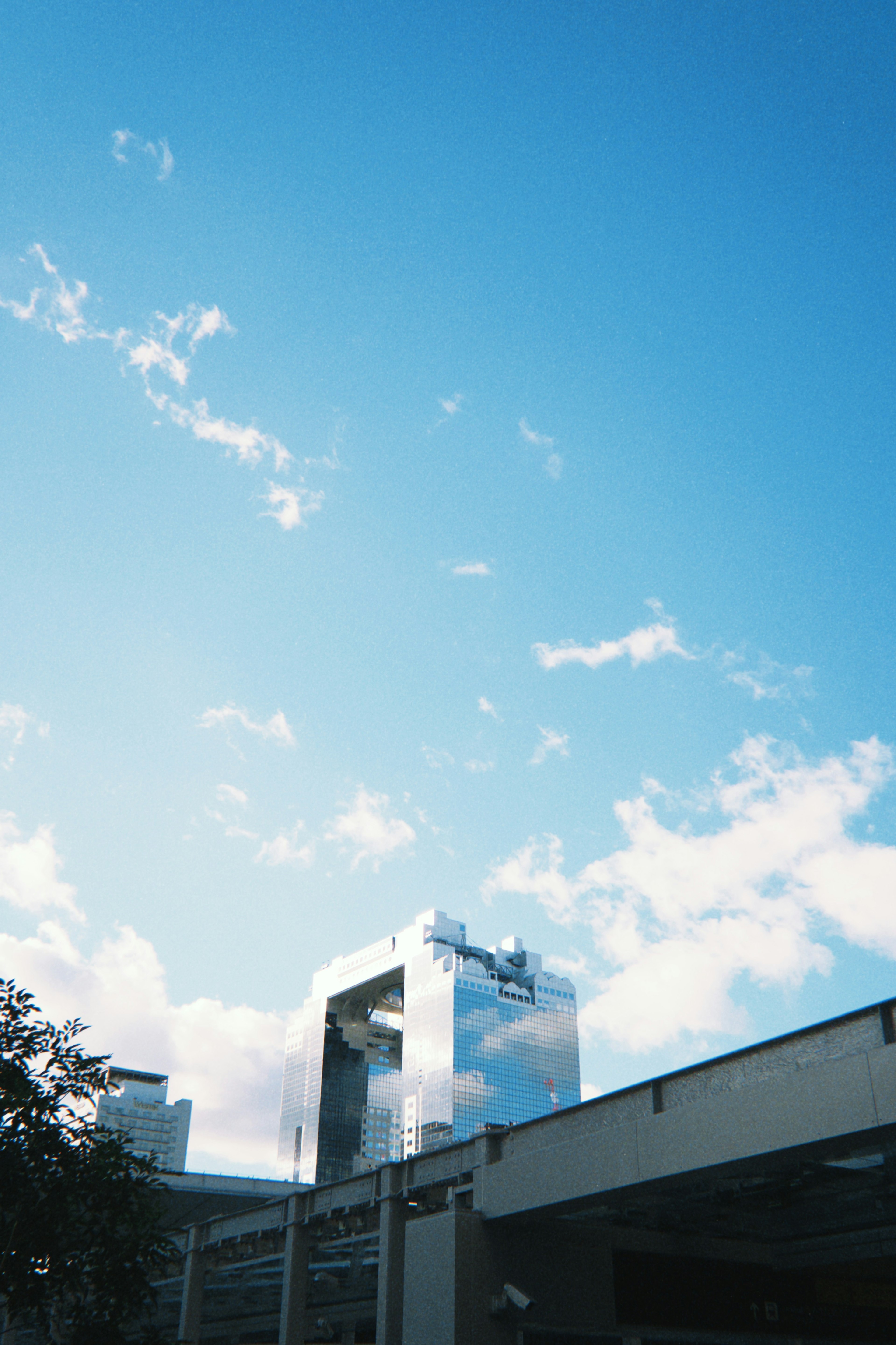 Edificio moderno parcialmente oscurecido por nubes bajo un cielo azul