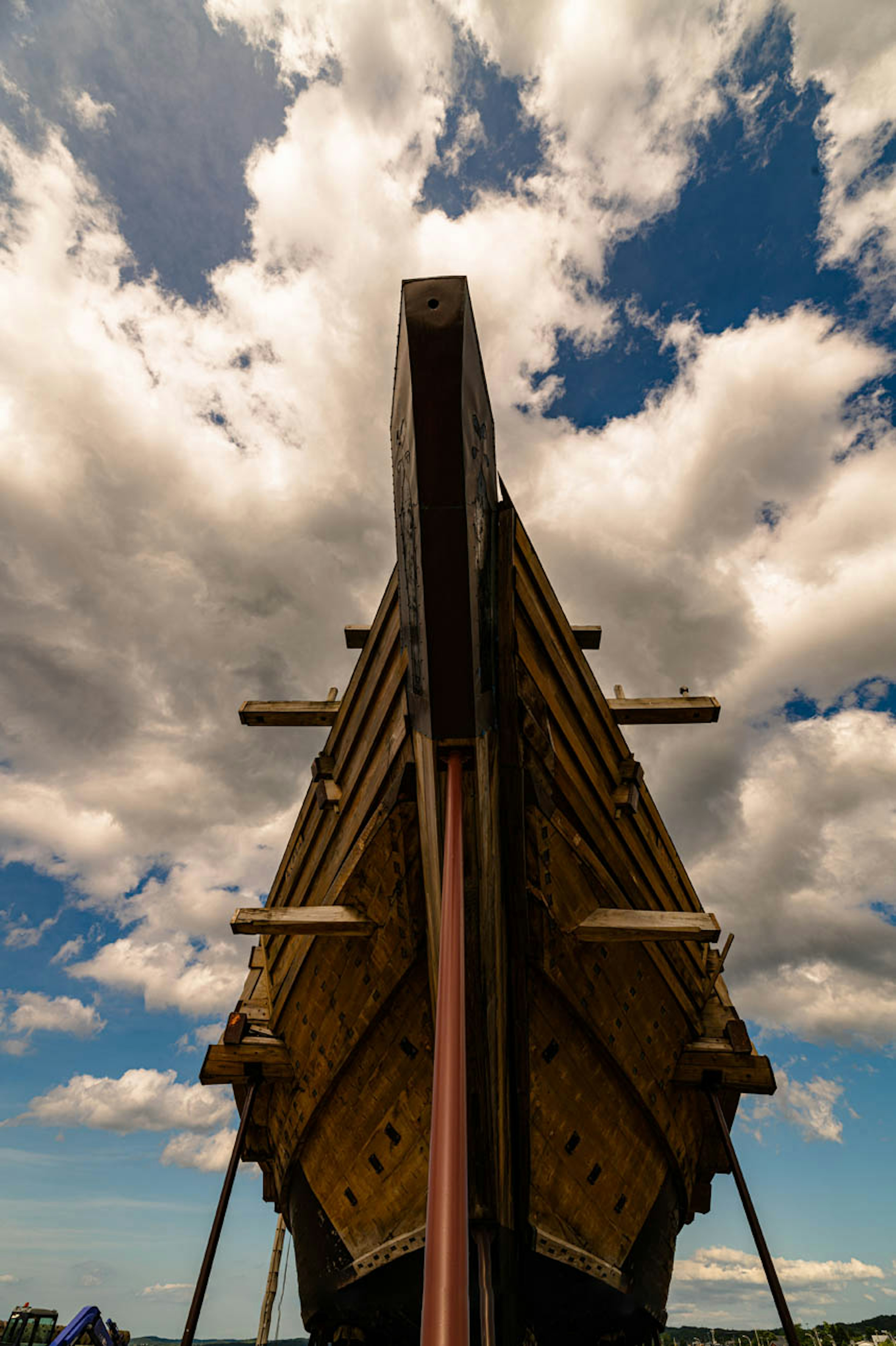 Image of a ship's stern viewed from below with blue sky and white clouds in the background