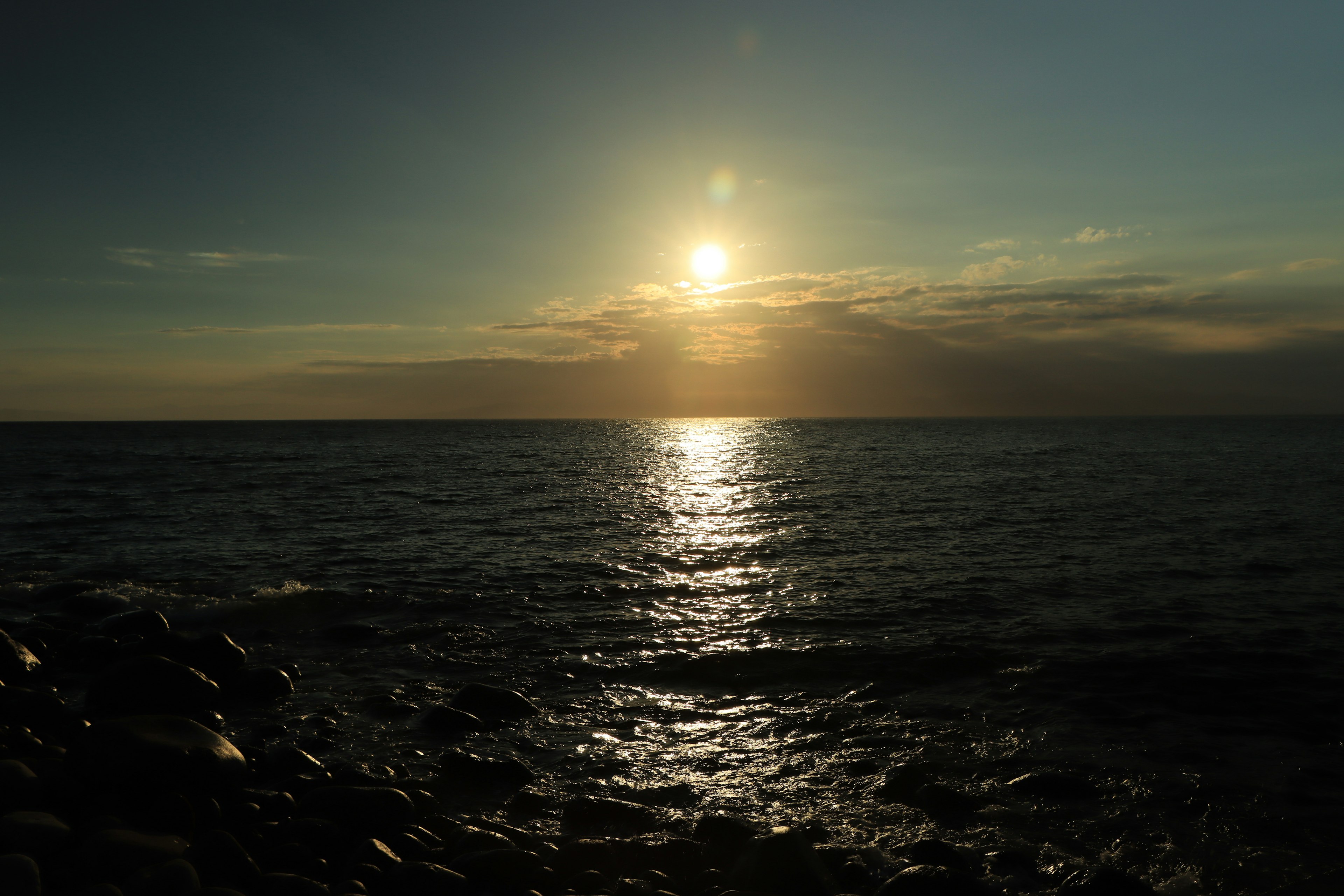 Sonnenuntergang über ruhigem Meer mit Reflexionen auf dem Wasser