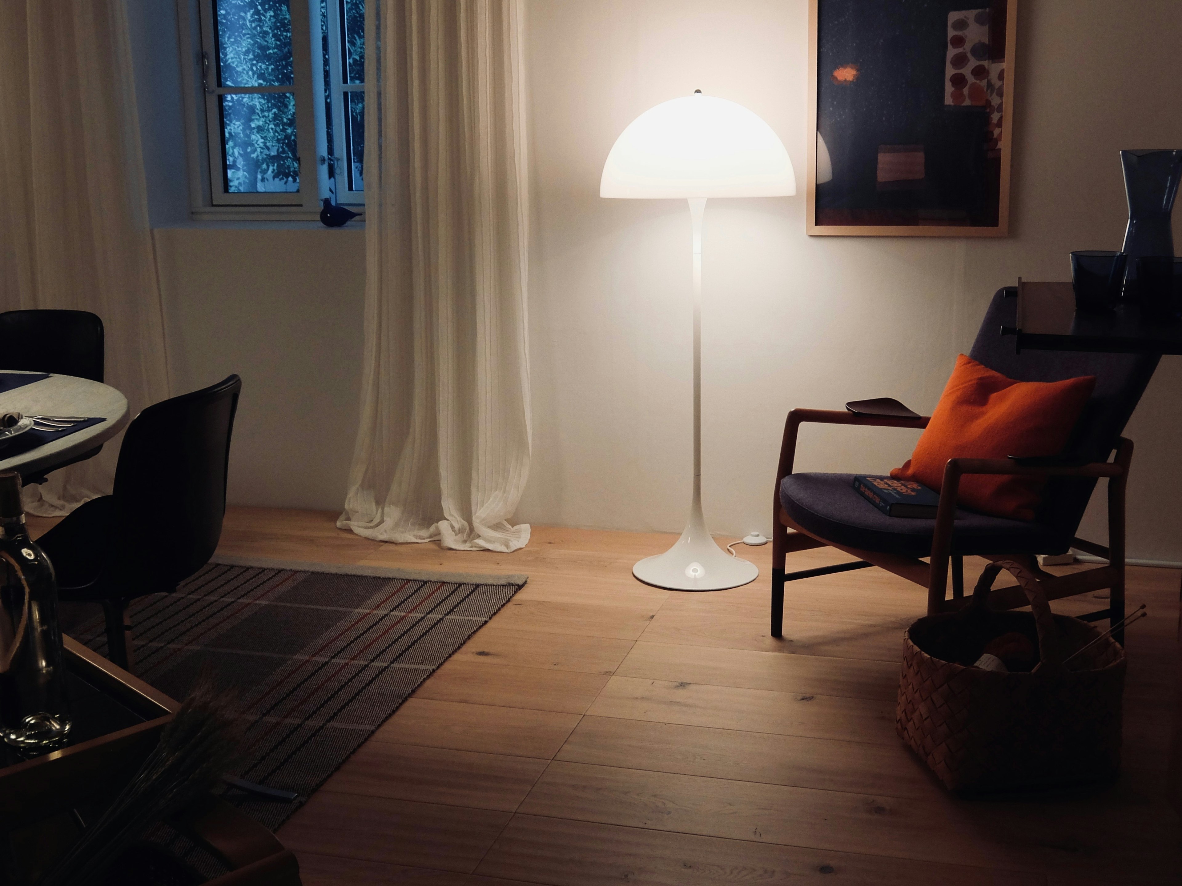 Coin douillet d'un salon avec une lampe lumineuse et un coussin orange