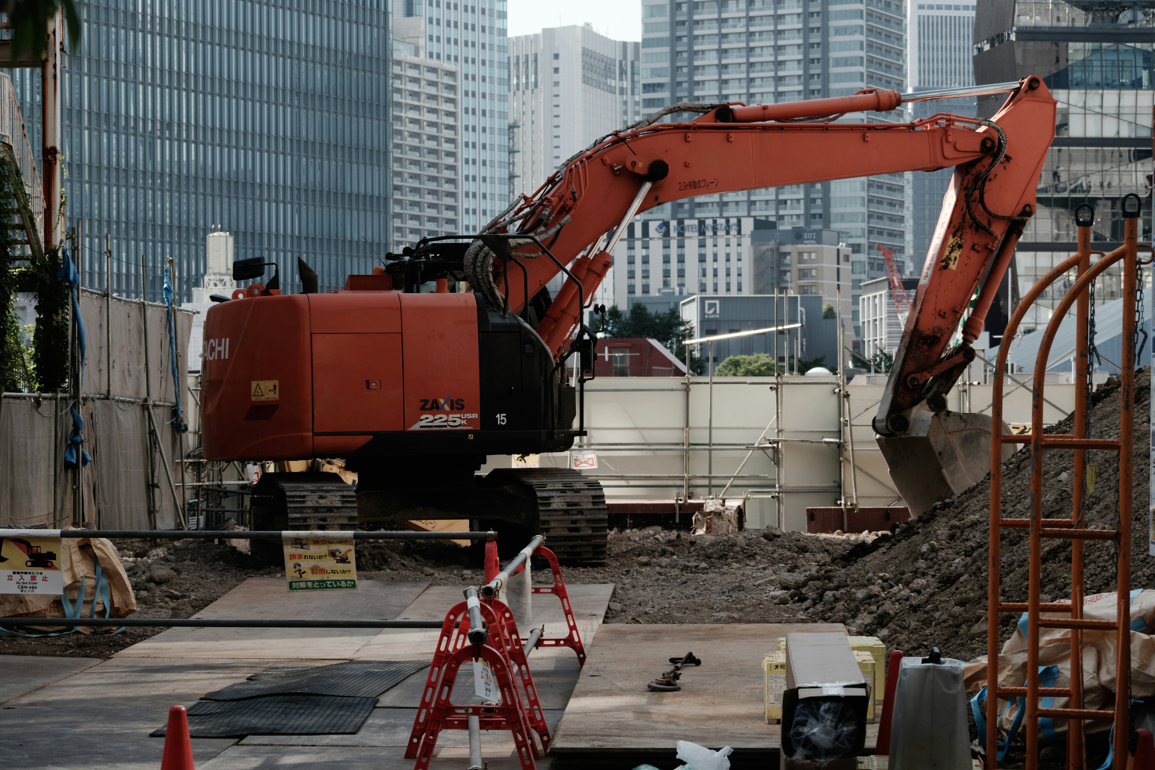 Excavatrice orange travaillant sur un chantier de construction en milieu urbain