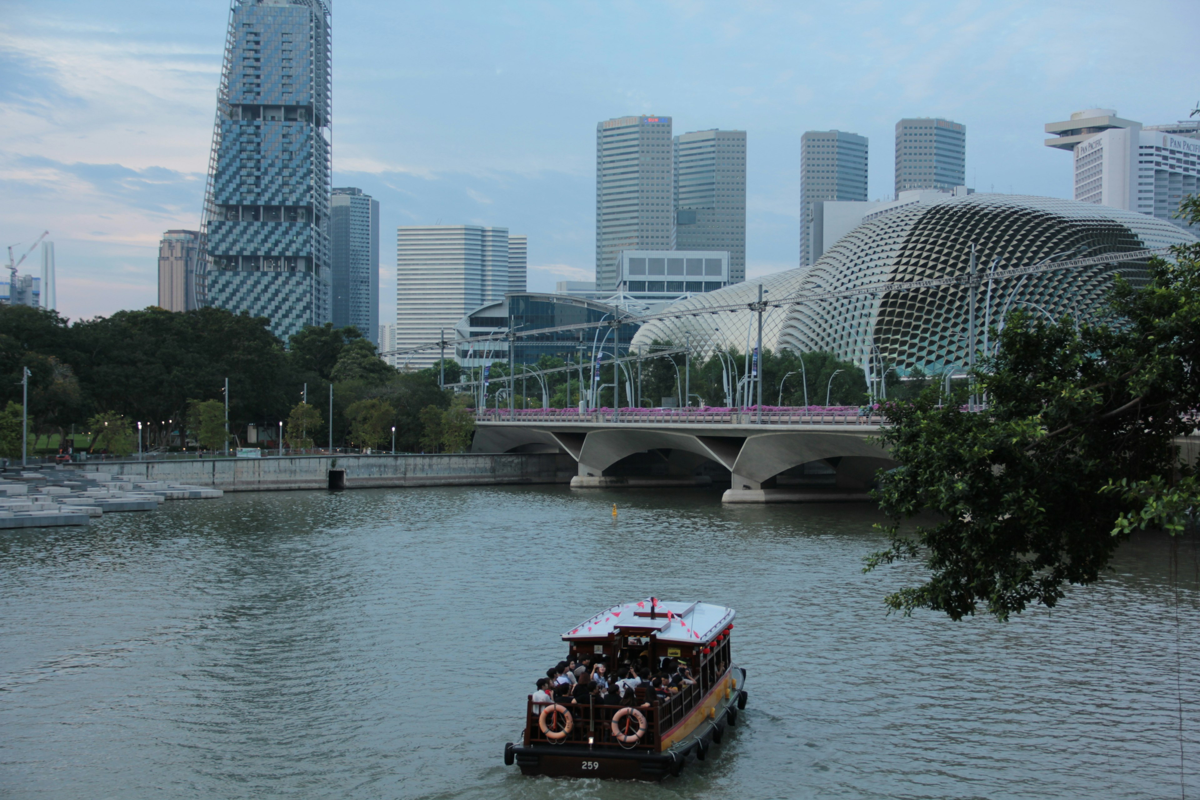 Kapal wisata yang berlayar di sungai Singapura dengan bangunan modern