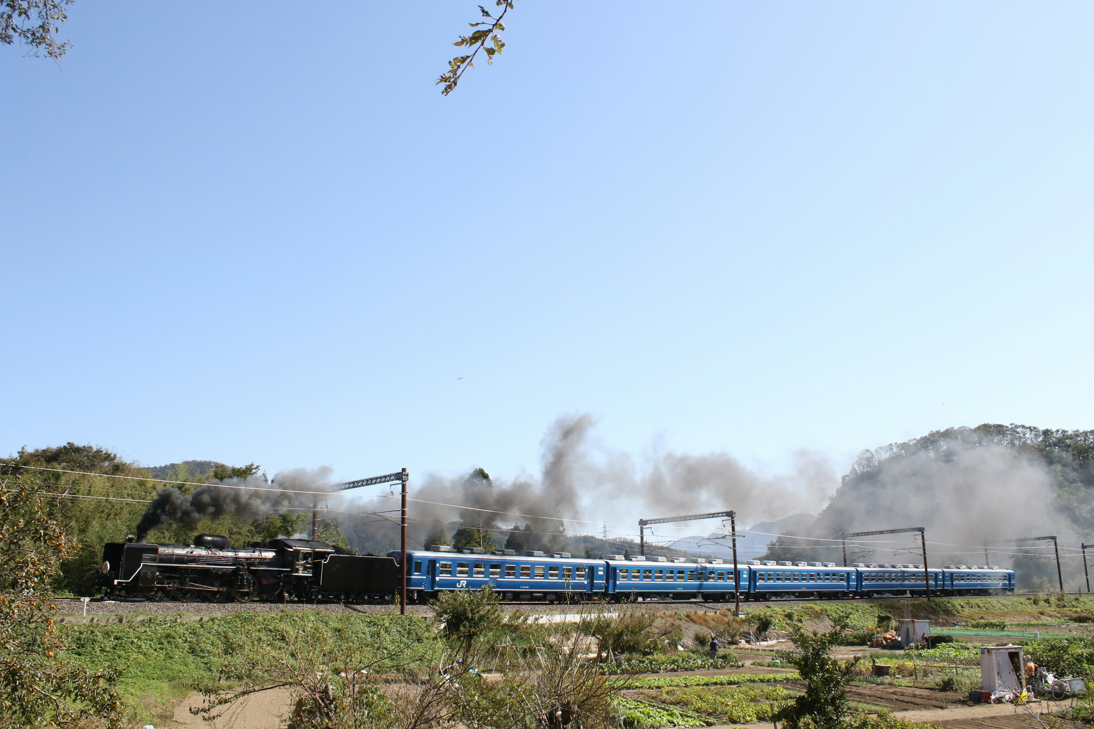 Ein blauer Zug, der an einer Dampflokomotive in einer malerischen Landschaft vorbeifährt