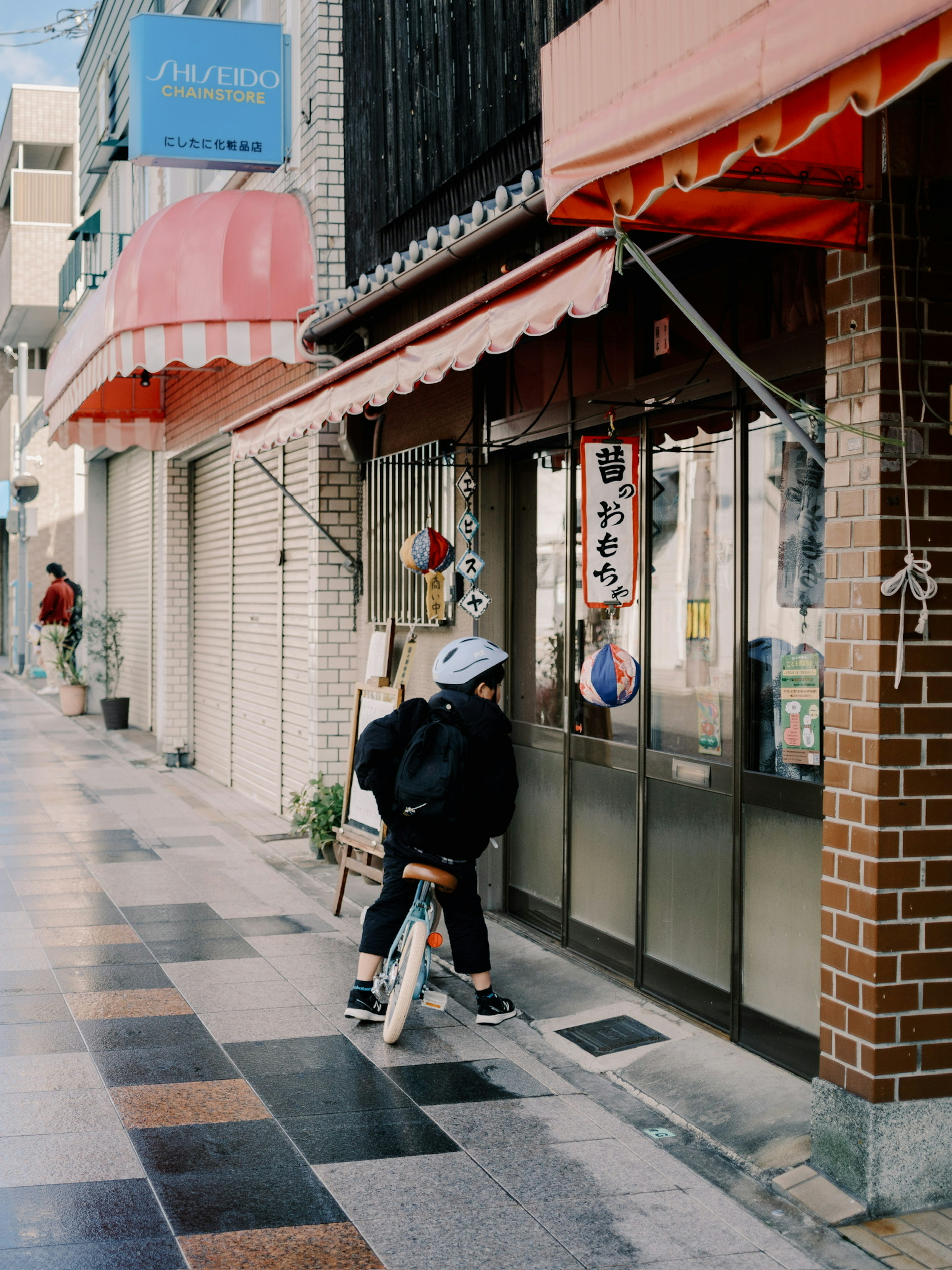 子供が自転車に乗って店の前にいる街の風景