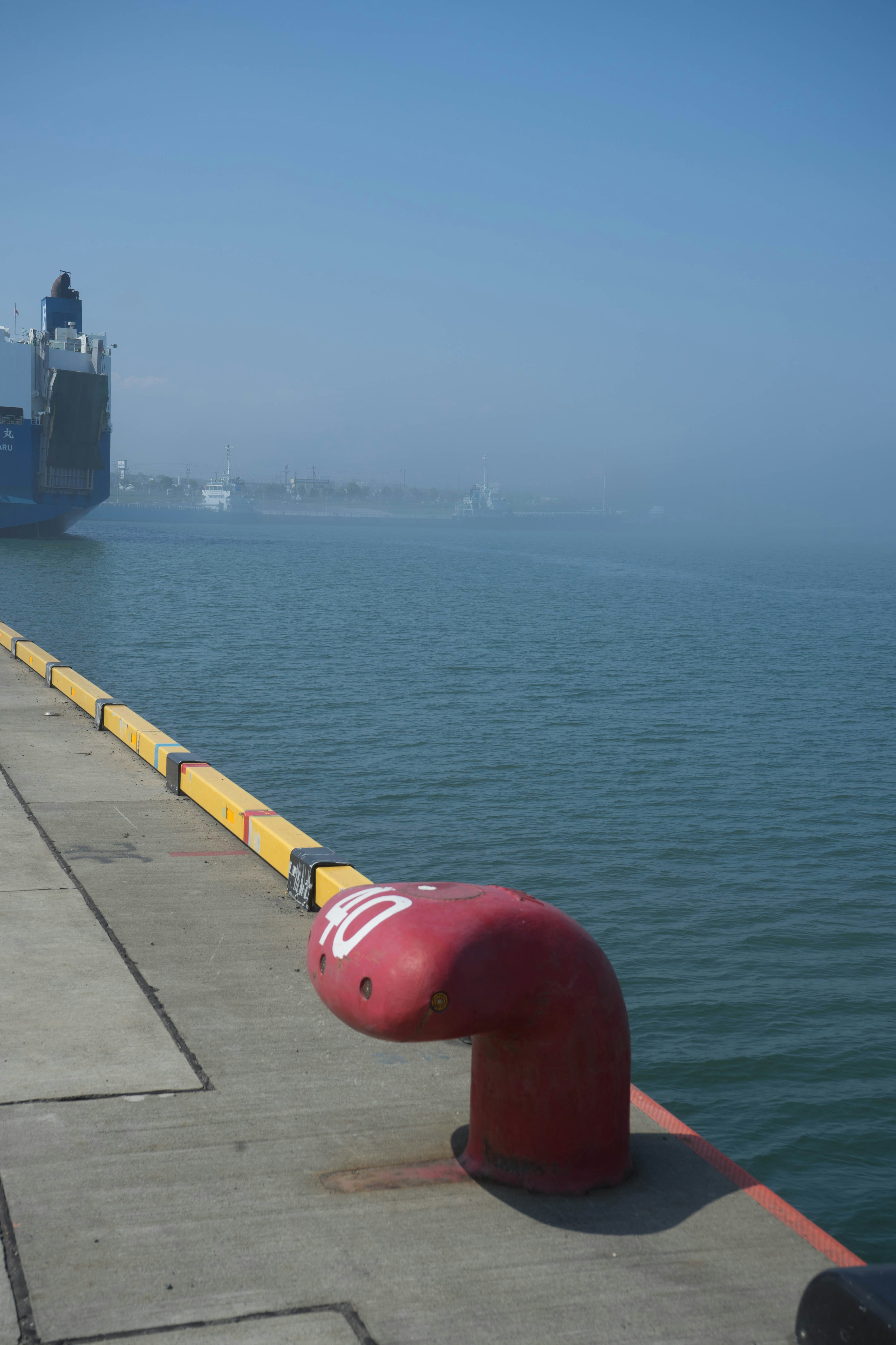 Roter Mooring-Bollard in einem Hafen mit einem Schiff im Hintergrund