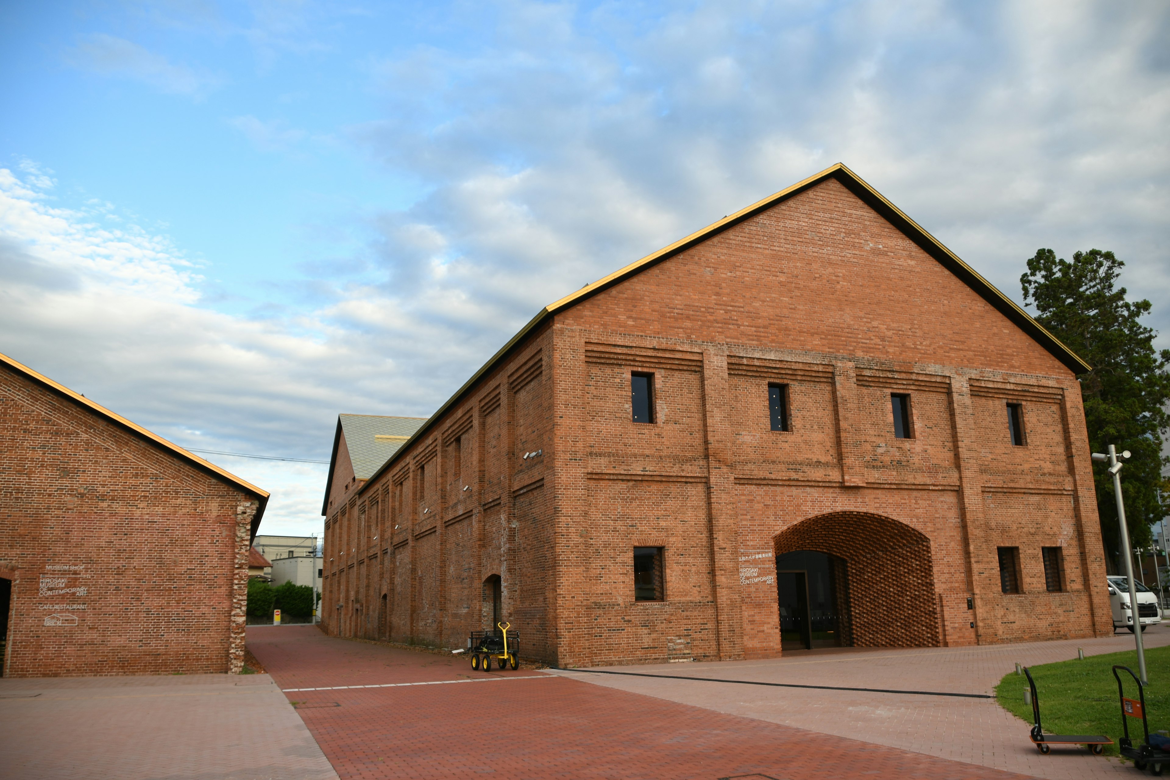 Rotes Backsteingebäude mit breitem Weg und bewölktem Himmel