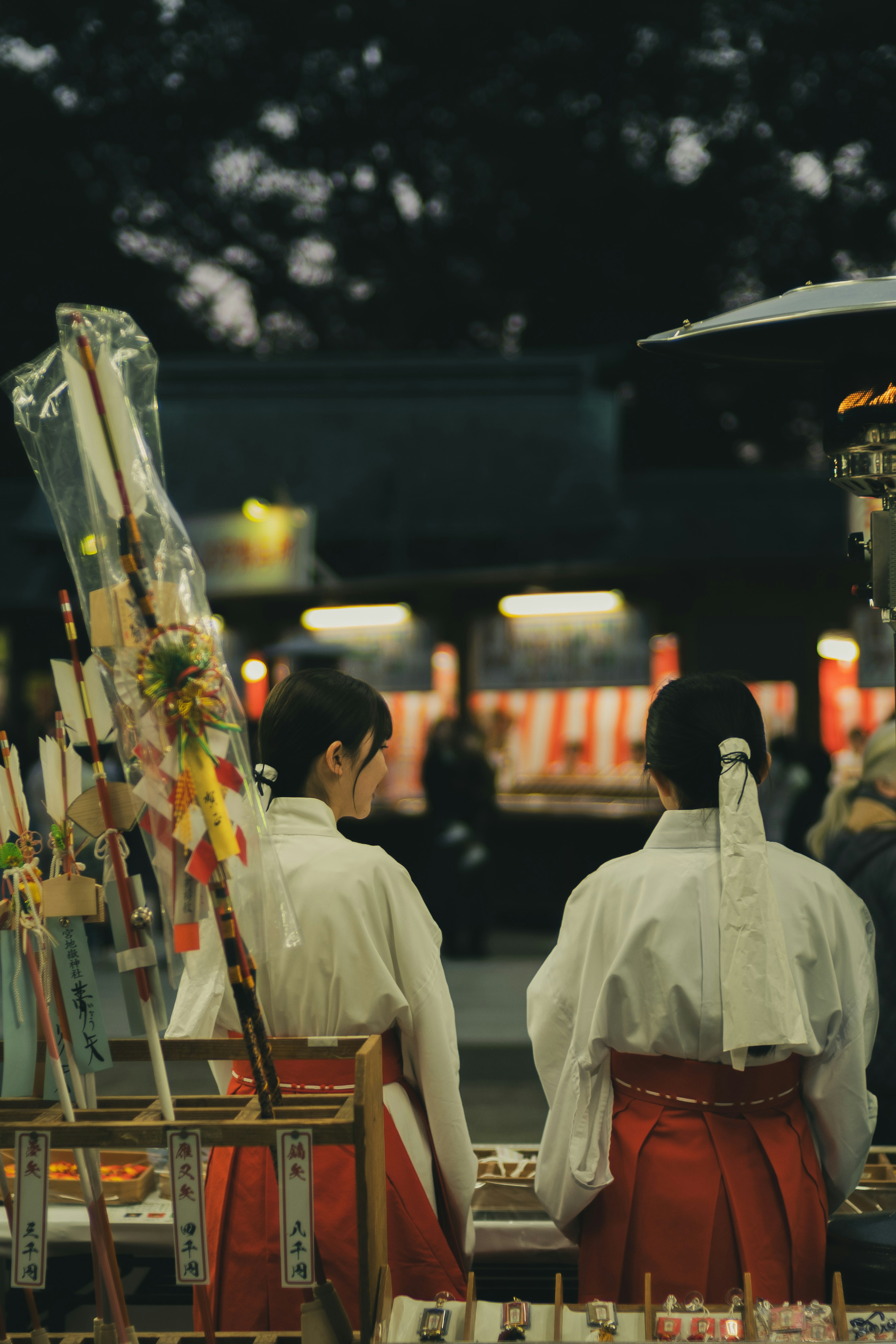 夜の神社で伝統的な衣装を着た女性たちが並んでいる