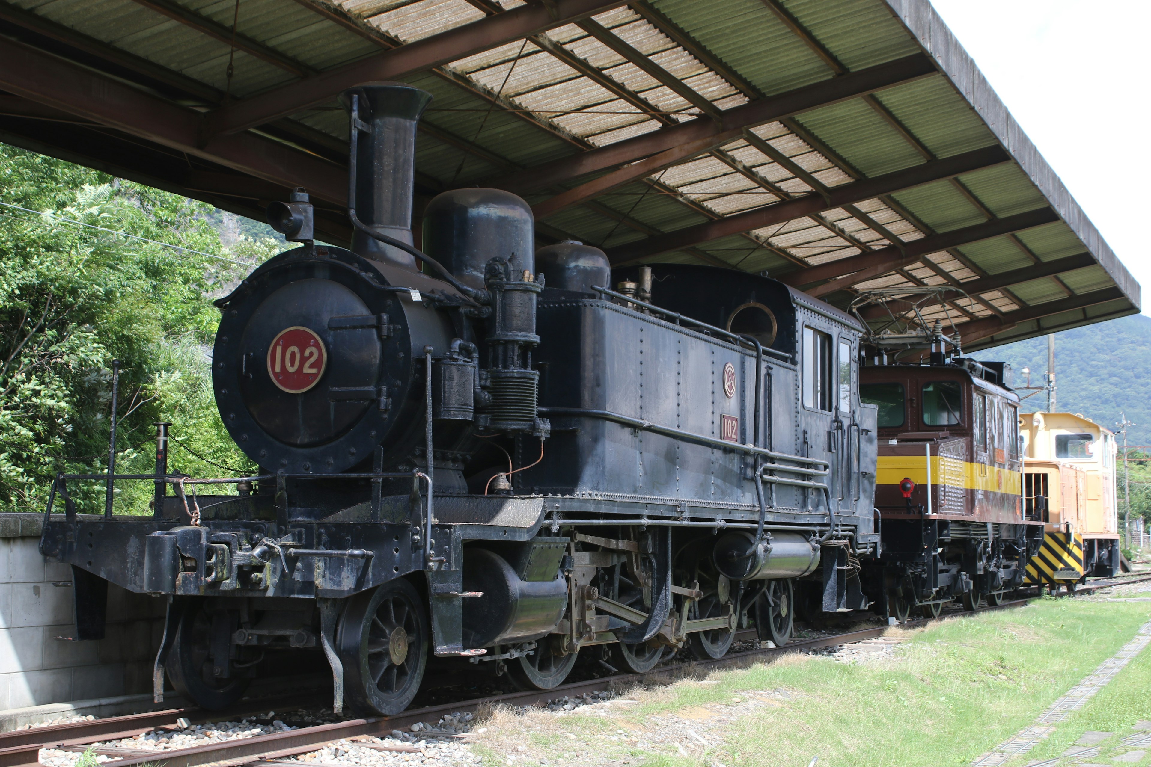 Una antigua locomotora de vapor estacionada bajo una plataforma cubierta