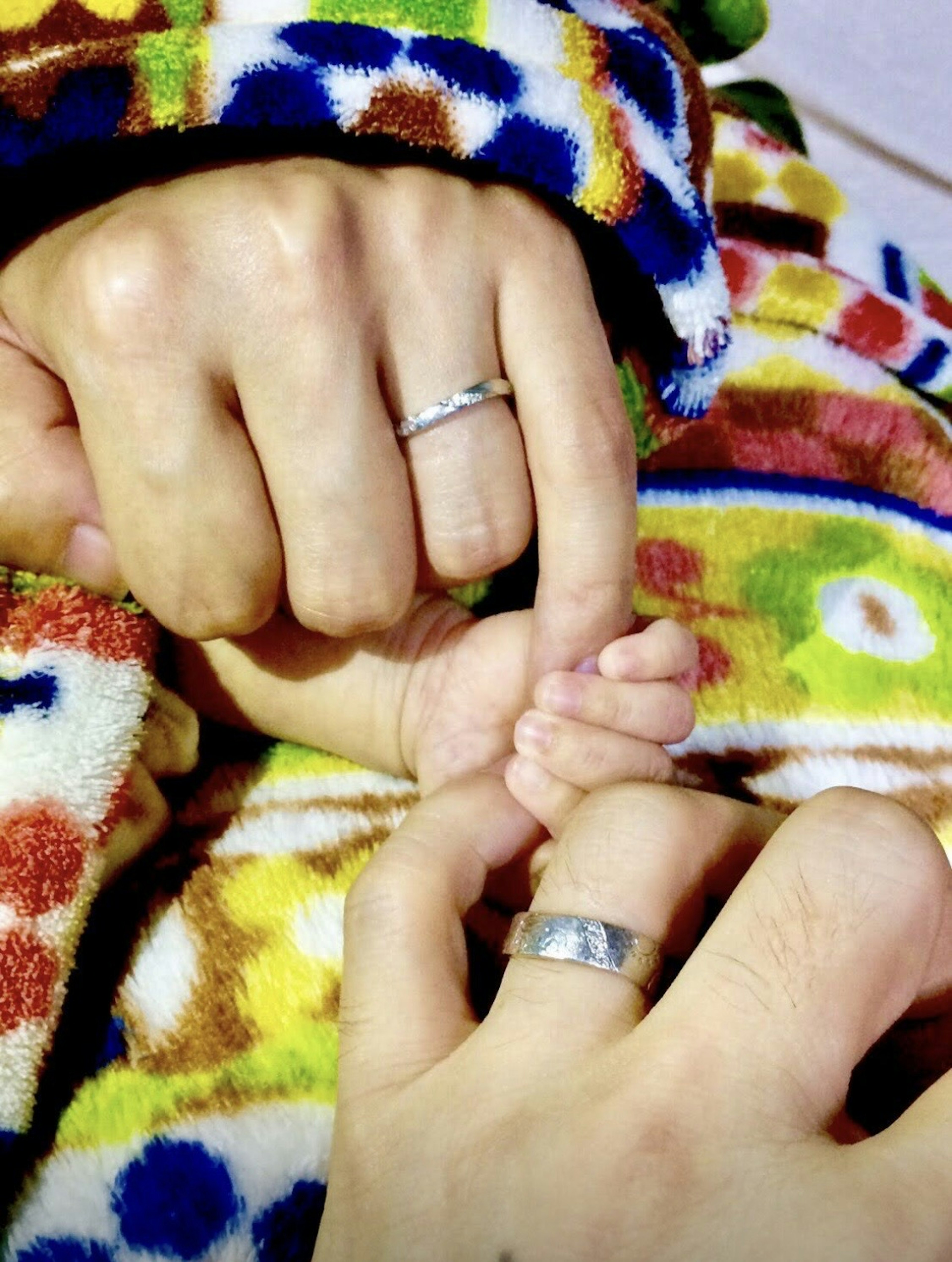 Momen hangat koneksi antara tangan tangan dewasa dengan cincin pernikahan dan tangan kecil bayi