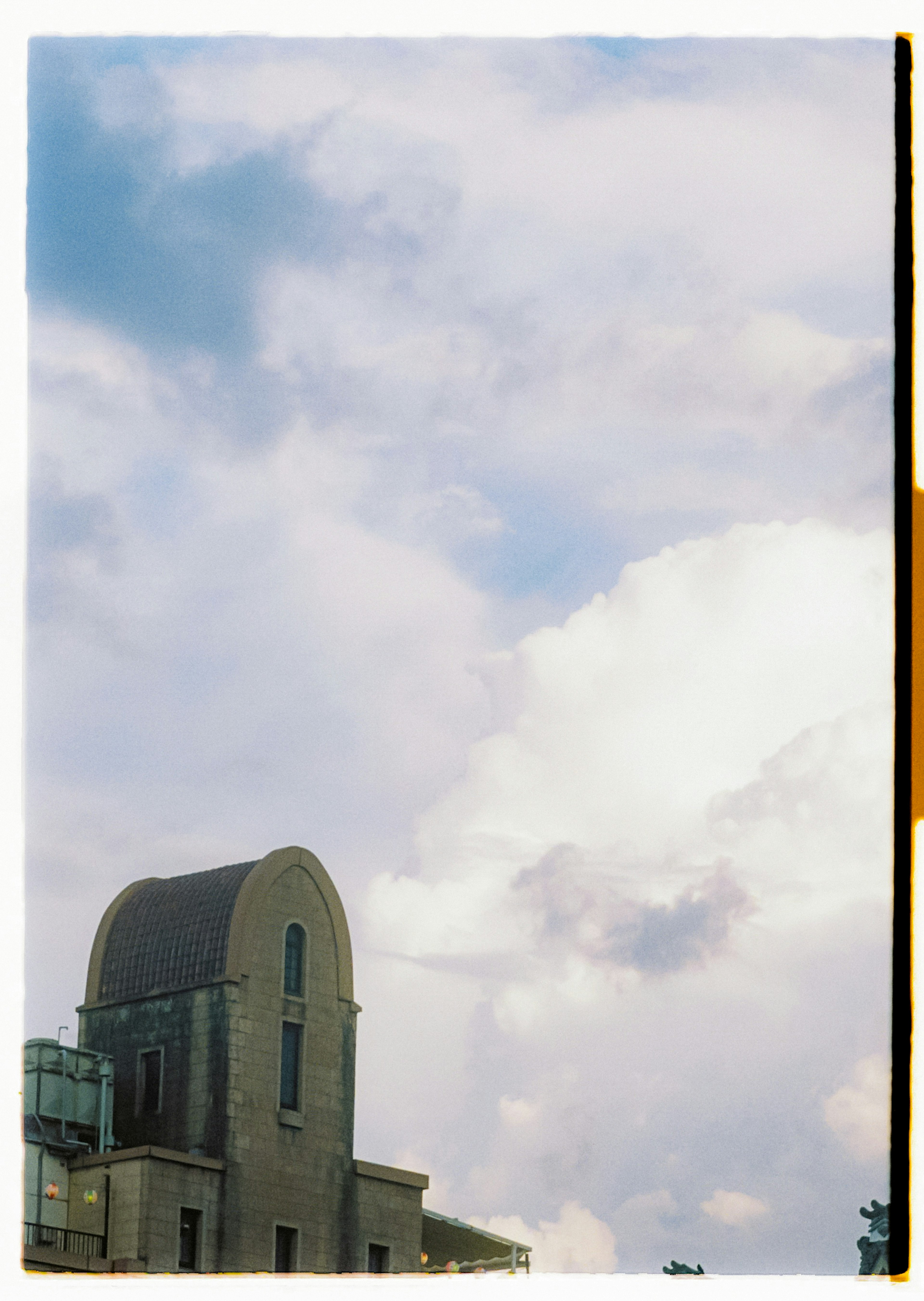 Part of a building under a cloudy blue sky