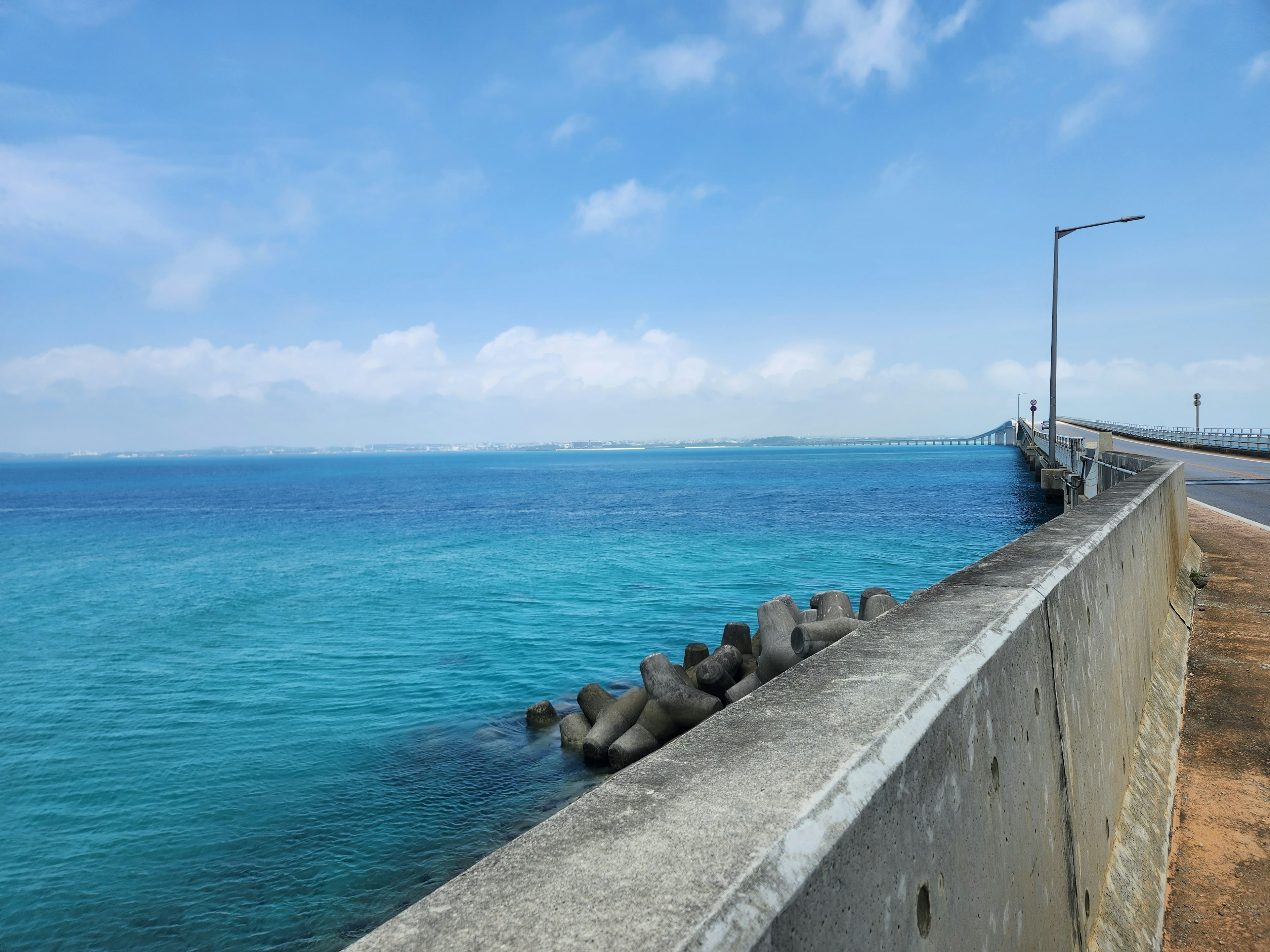 青い海と空の景色を背景にしたコンクリートの橋