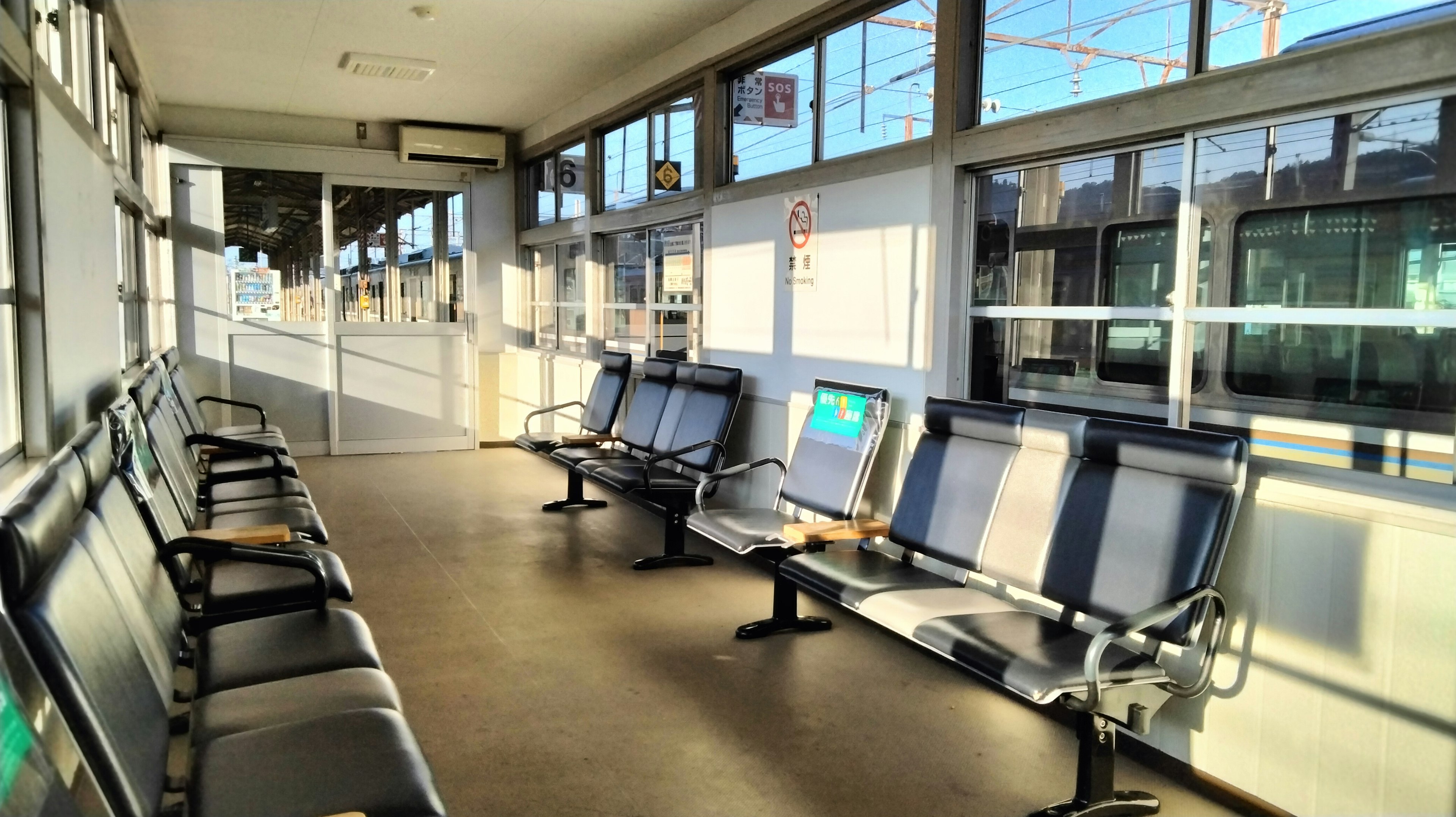 Área de espera en una estación de tren con filas de asientos y luz natural