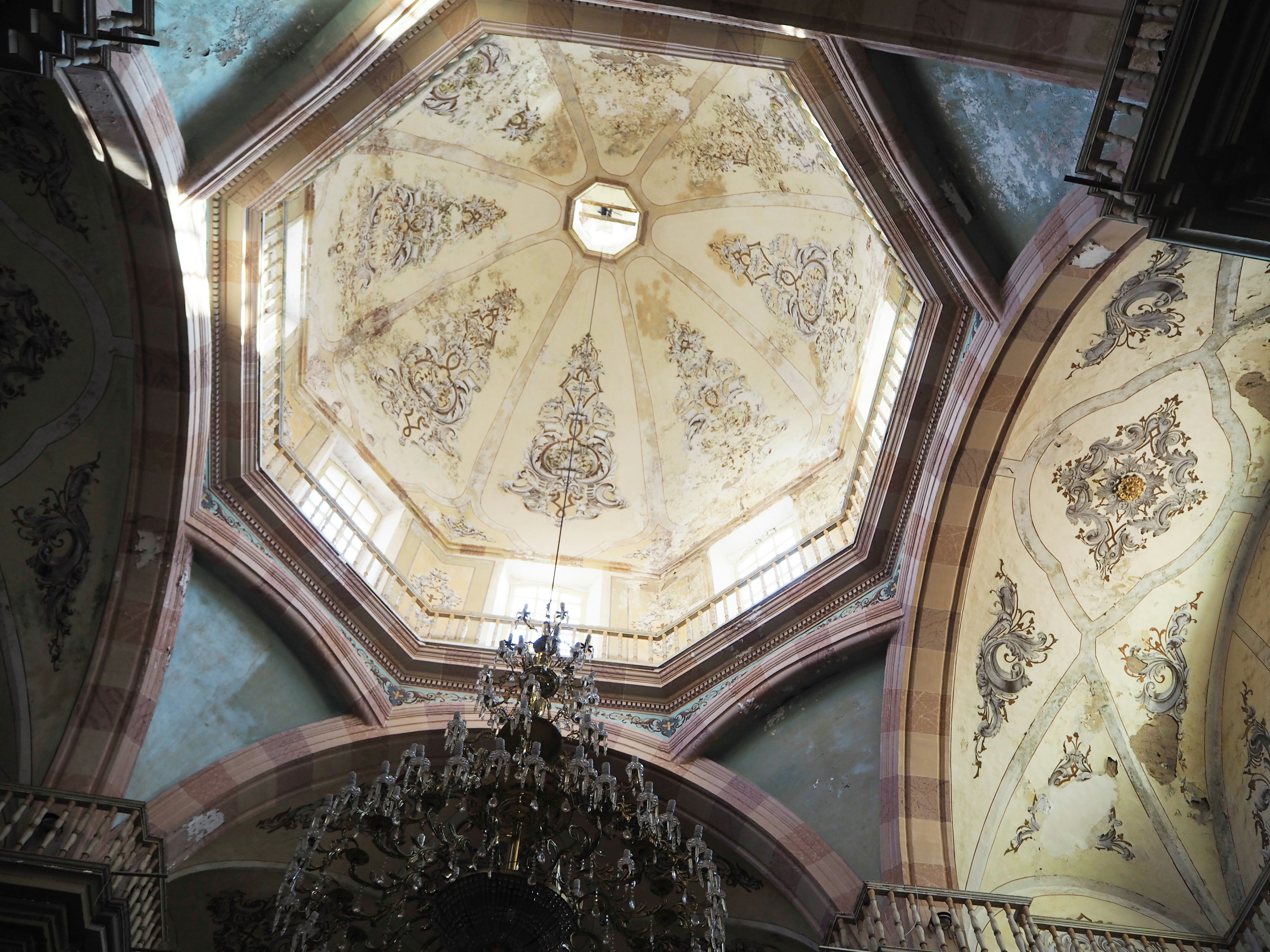 Interior view of an octagonal ceiling with intricate decorations and a chandelier