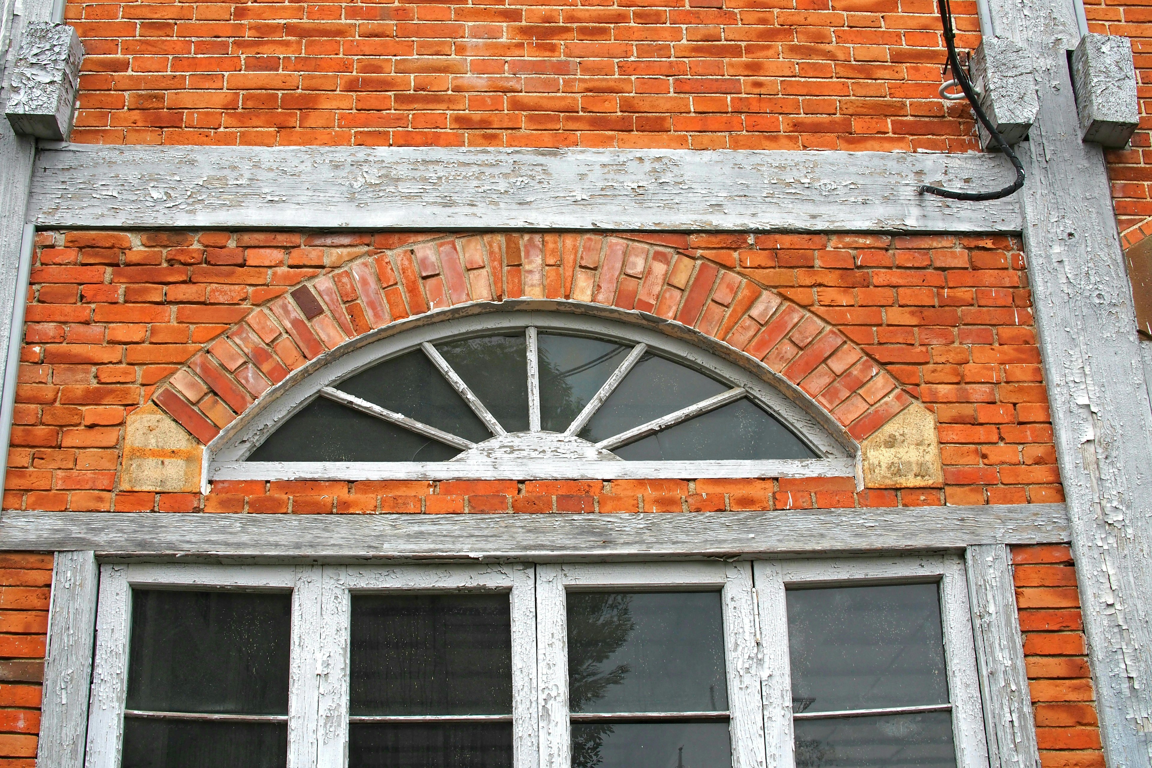 Rote Ziegelwand mit Holzfensterrahmen und Bogenform