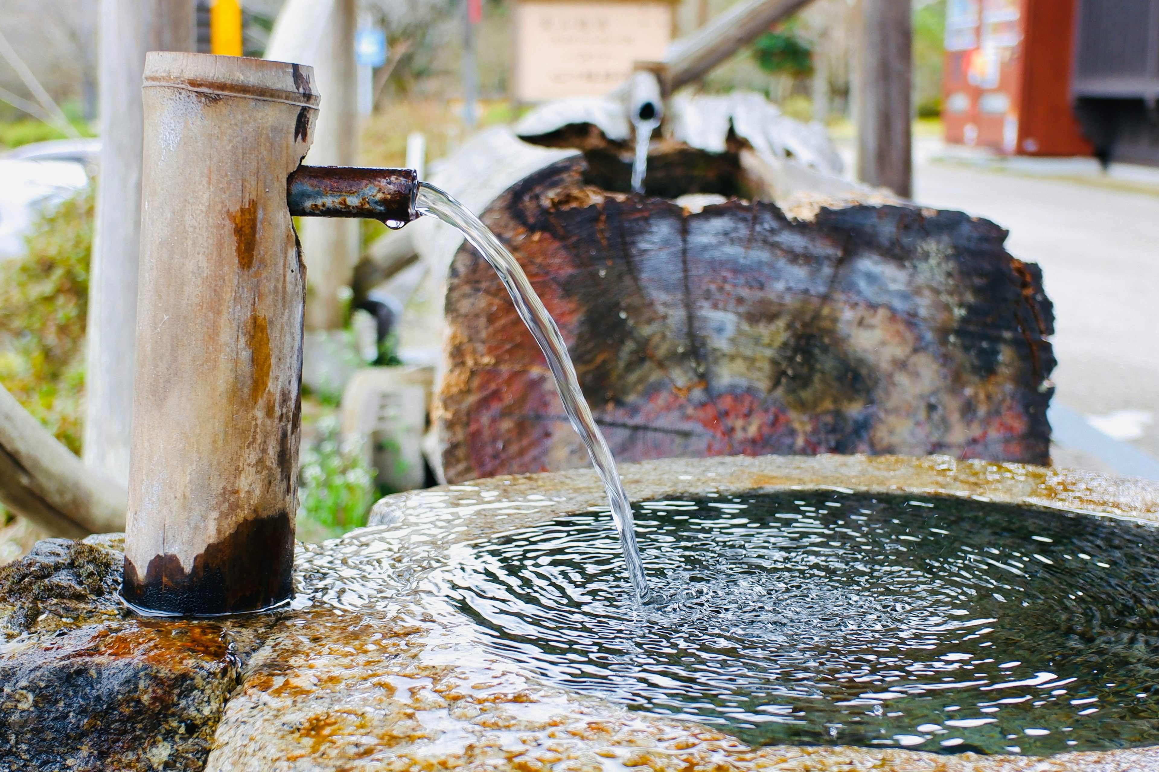 Eau s'écoulant d'un robinet en bambou dans un bassin en pierre