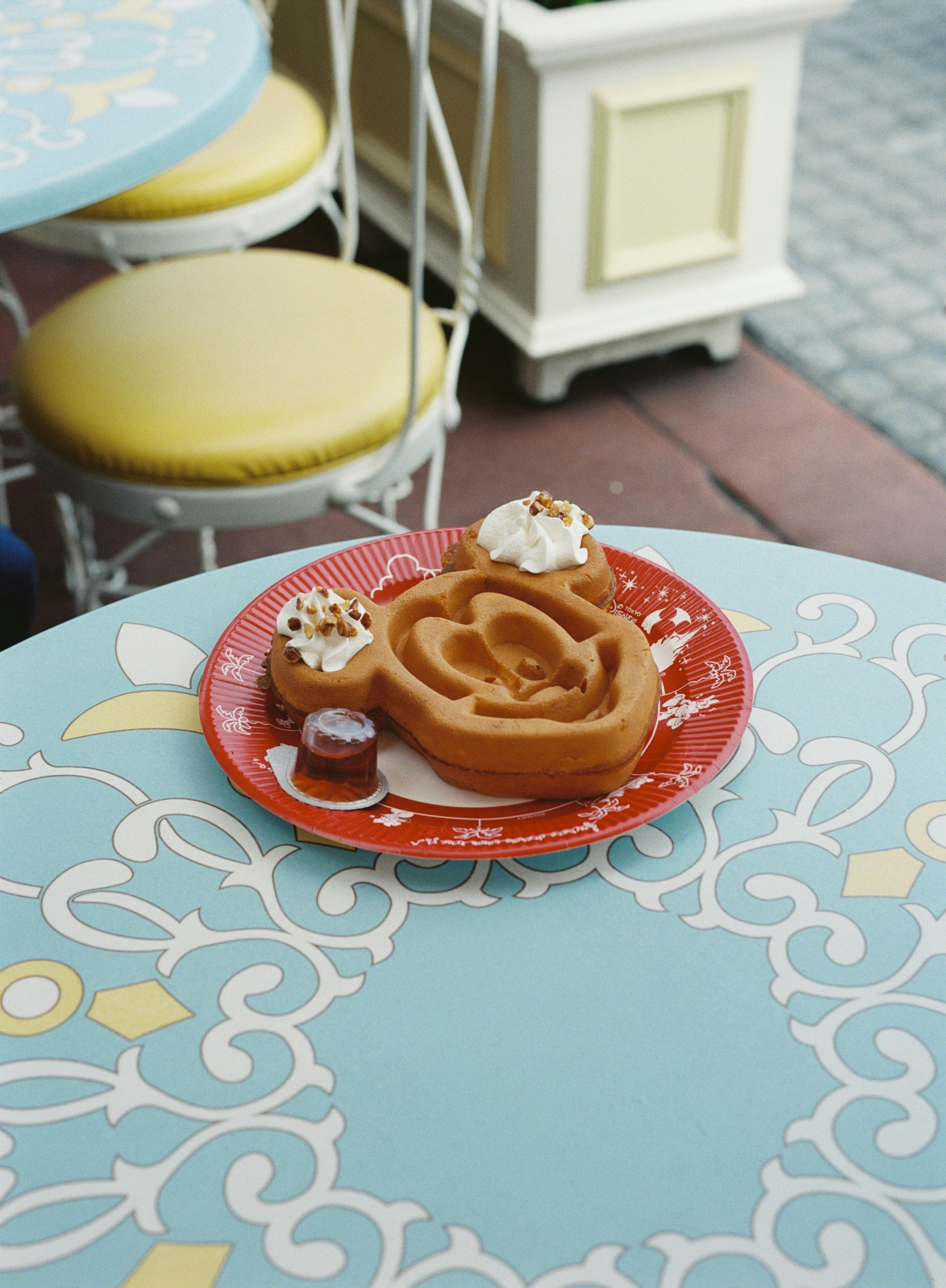 Mickey Mouse shaped waffle dessert with cream on a decorative plate