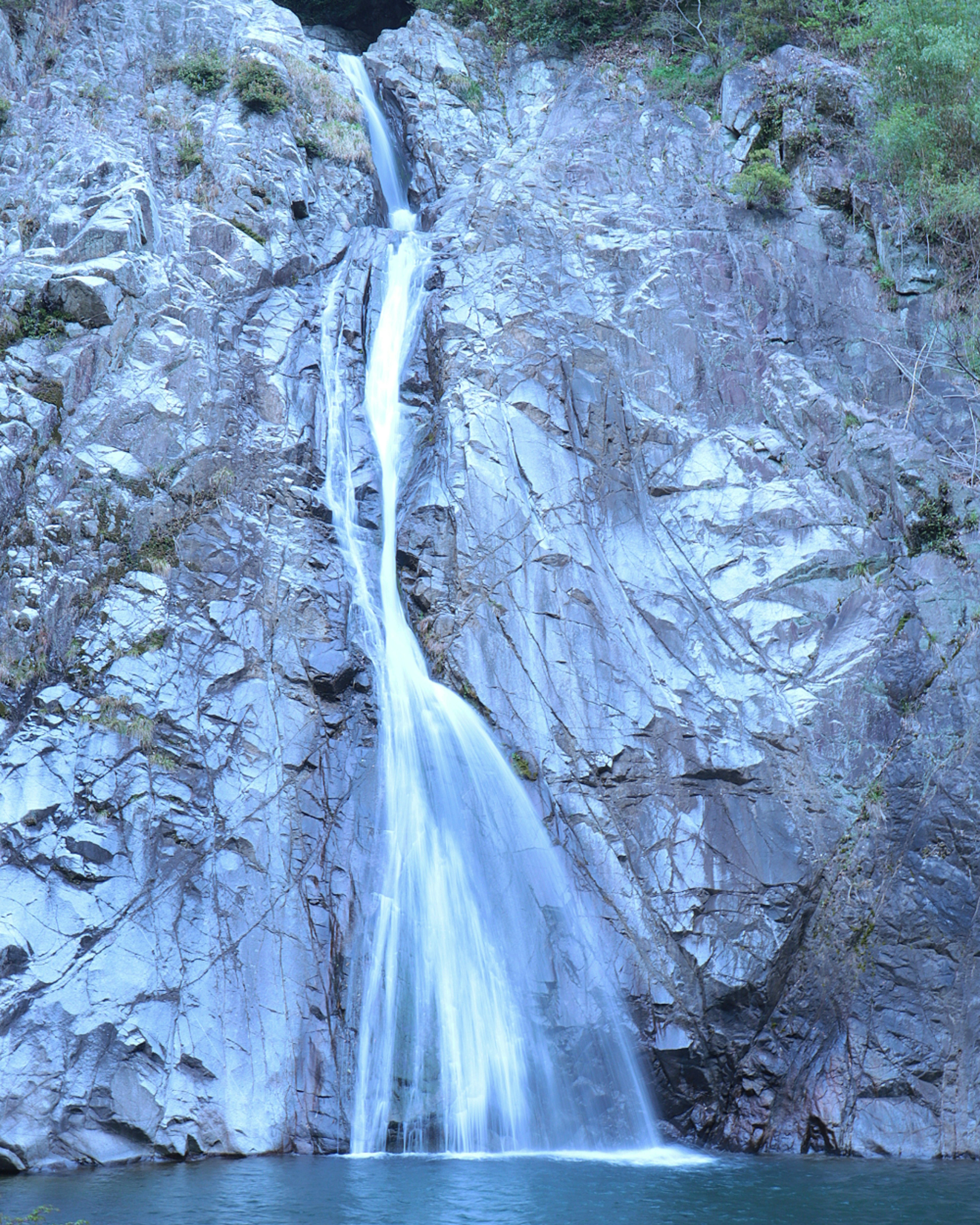 Una cascata blu che scorre giù per le scogliere rocciose