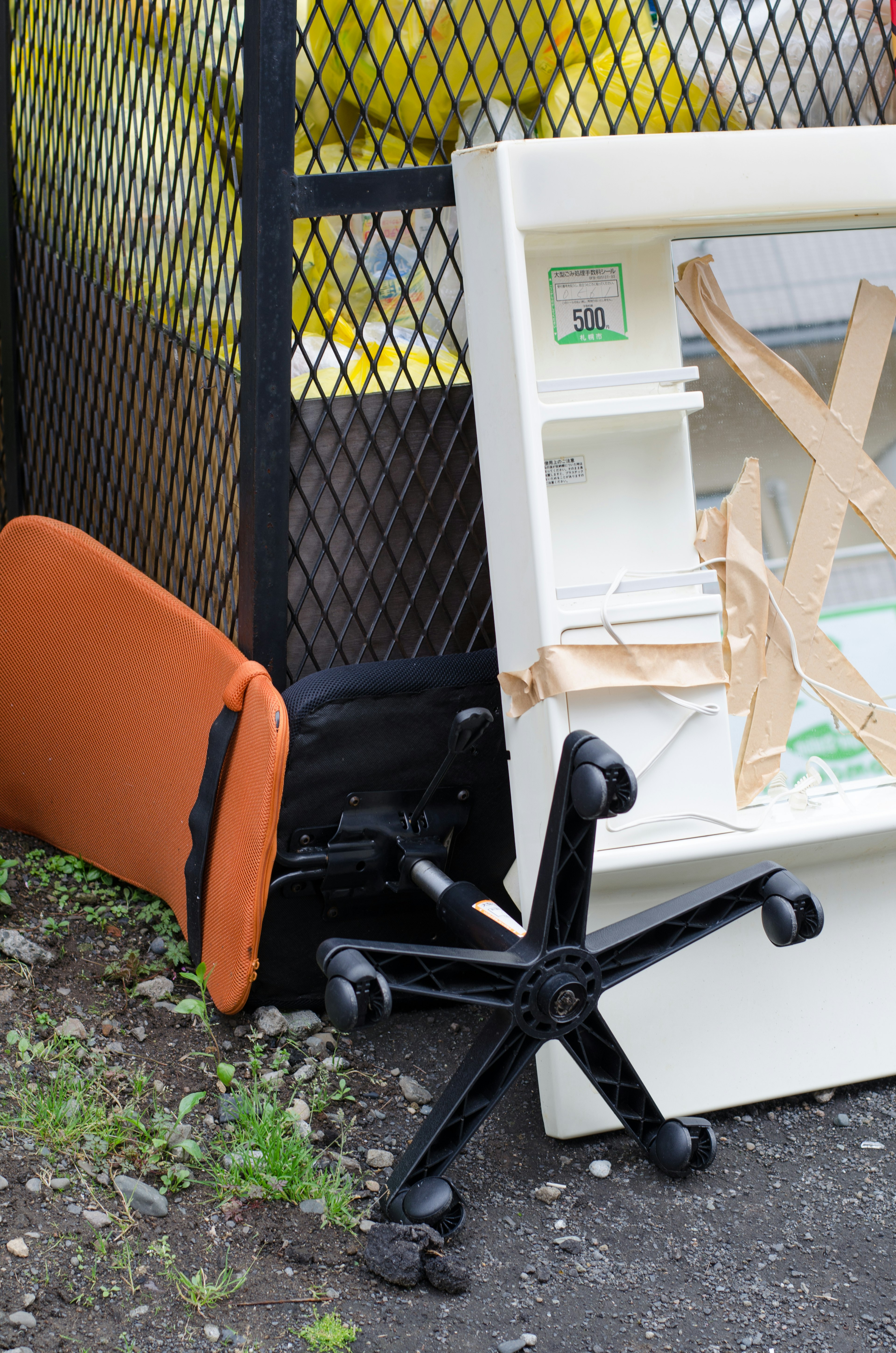 Tas de meubles de bureau abandonnés avec une chaise et un cabinet de fichiers allongés