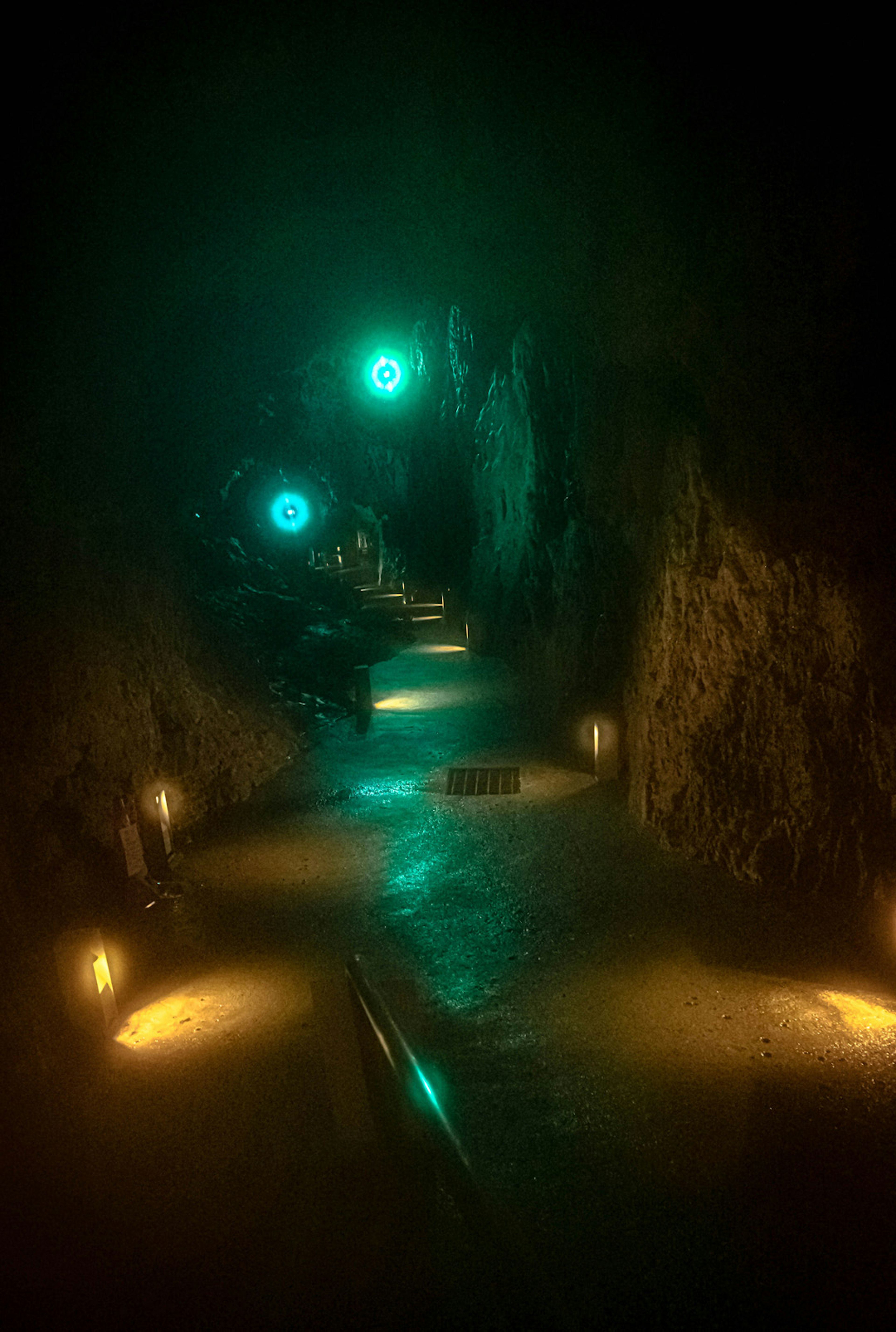 Túnel débilmente iluminado con luces verdes y naranjas