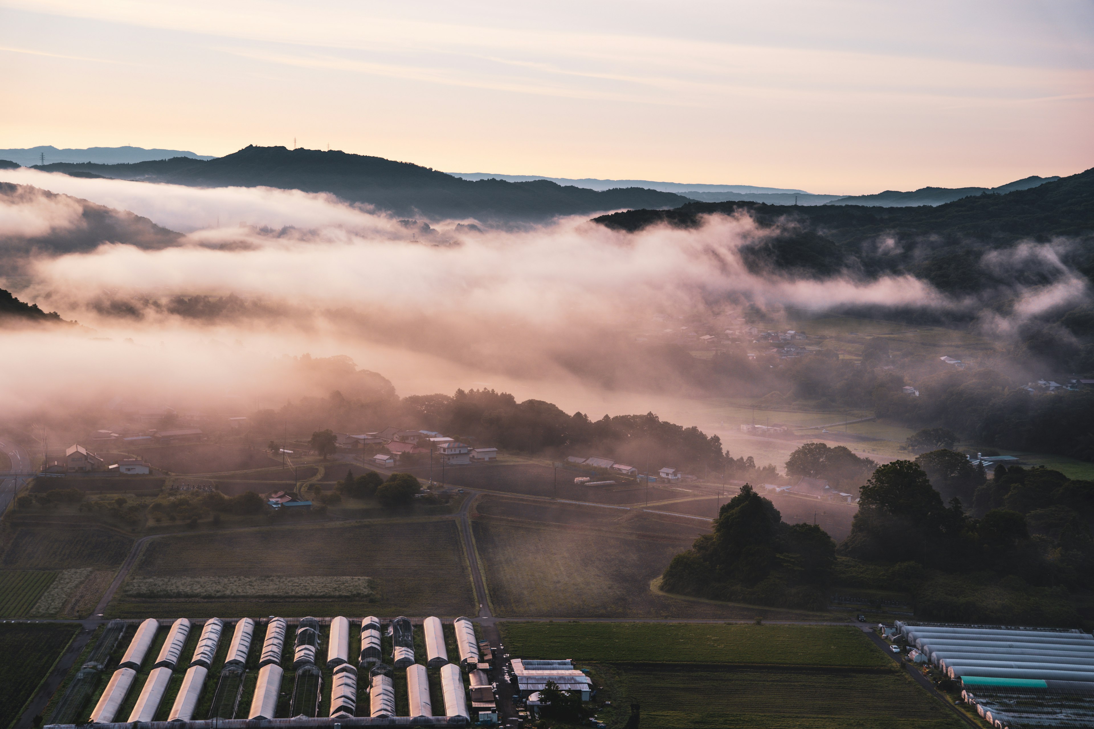 Vista aérea de montañas brumosas y tierras agrícolas al amanecer