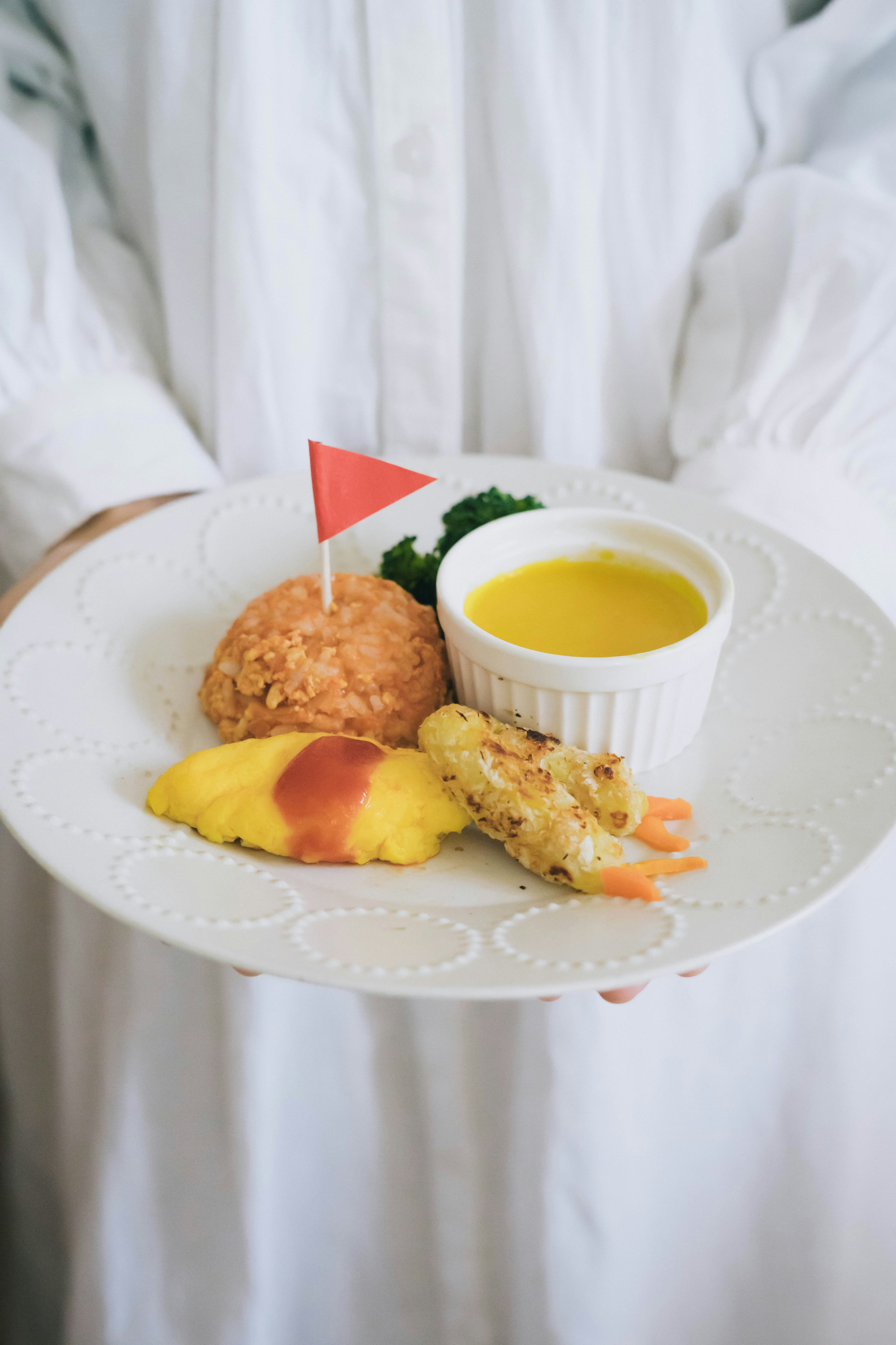 A plate of food held by a person in a white outfit