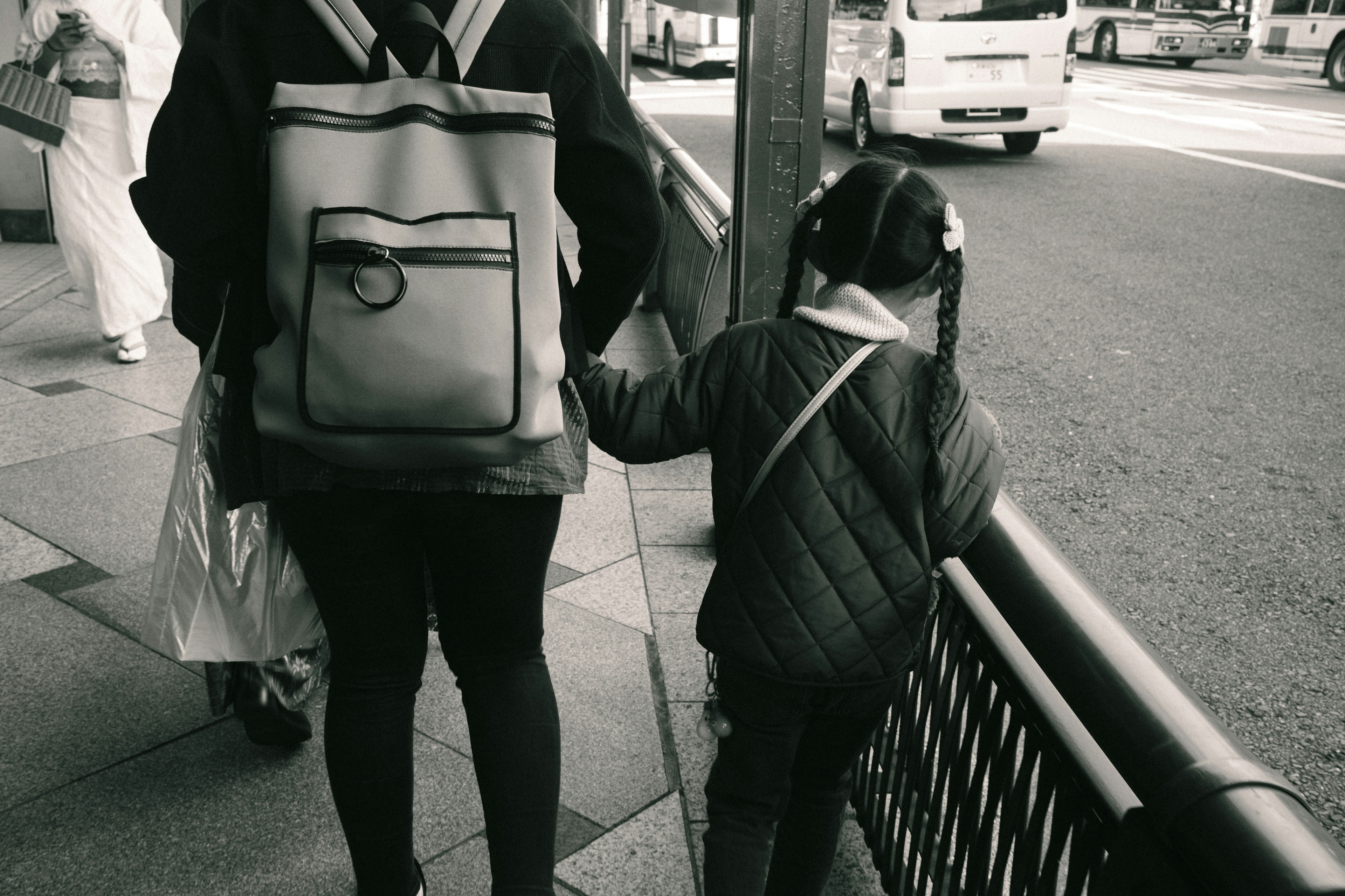 Black and white image of a parent and child walking hand in hand