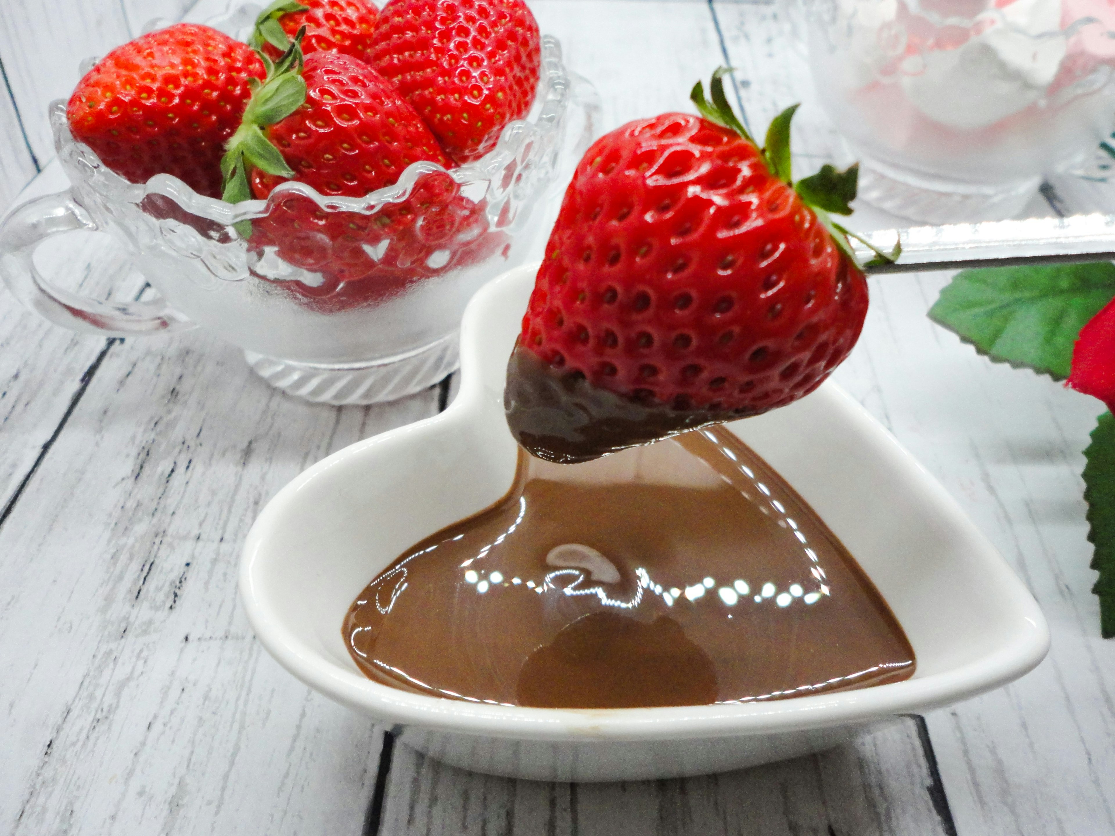 Fresca fragola immersa in salsa di cioccolato in un piatto a forma di cuore