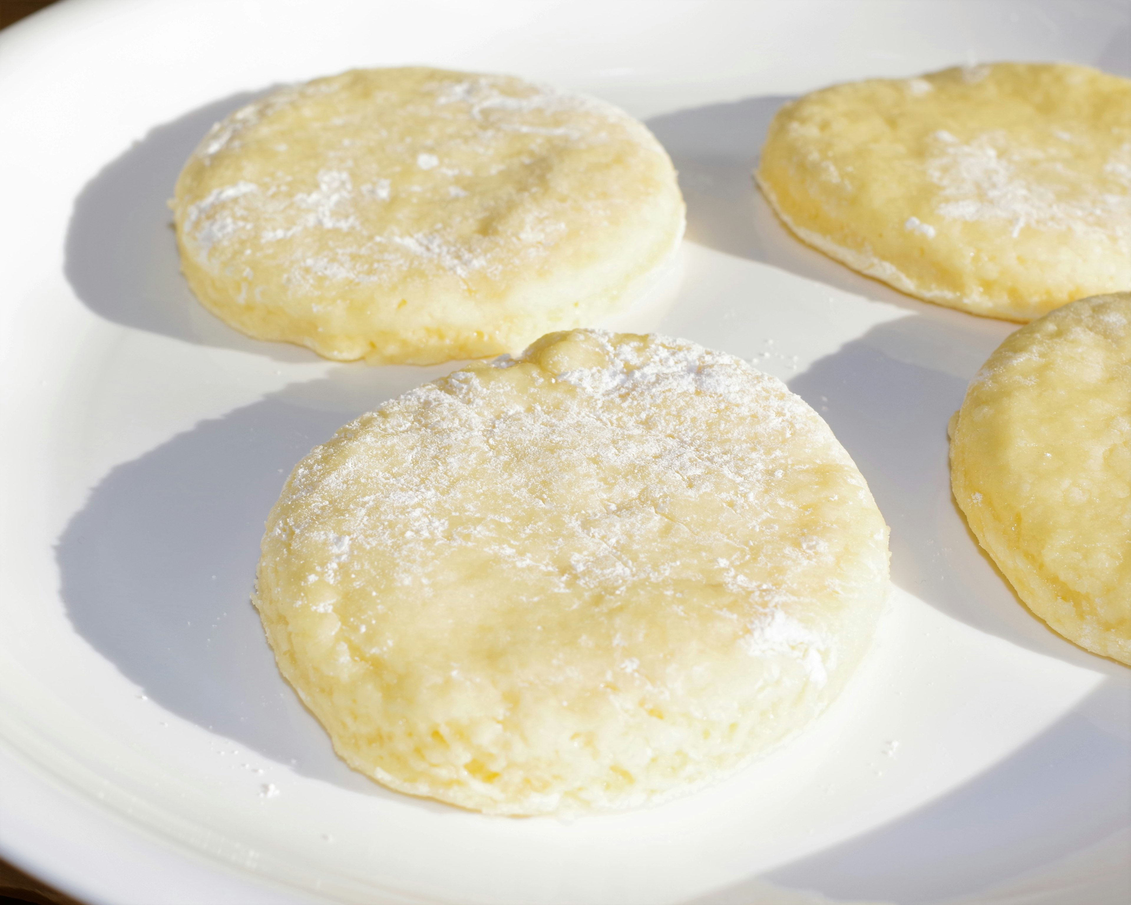 Biscuits ronds saupoudrés de sucre glace sur une assiette blanche