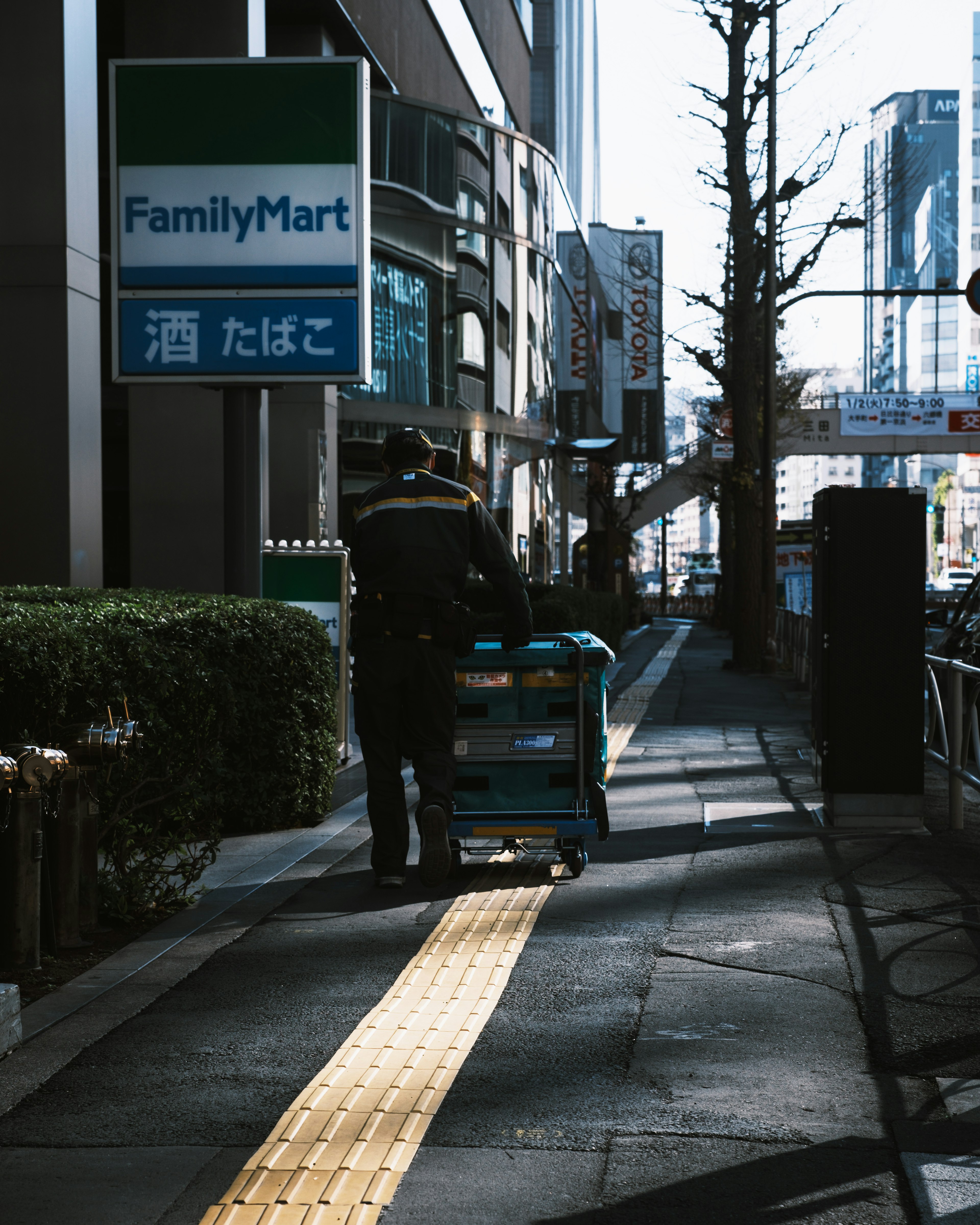 ファミリーマートの看板の下でカートを押す人の後ろ姿