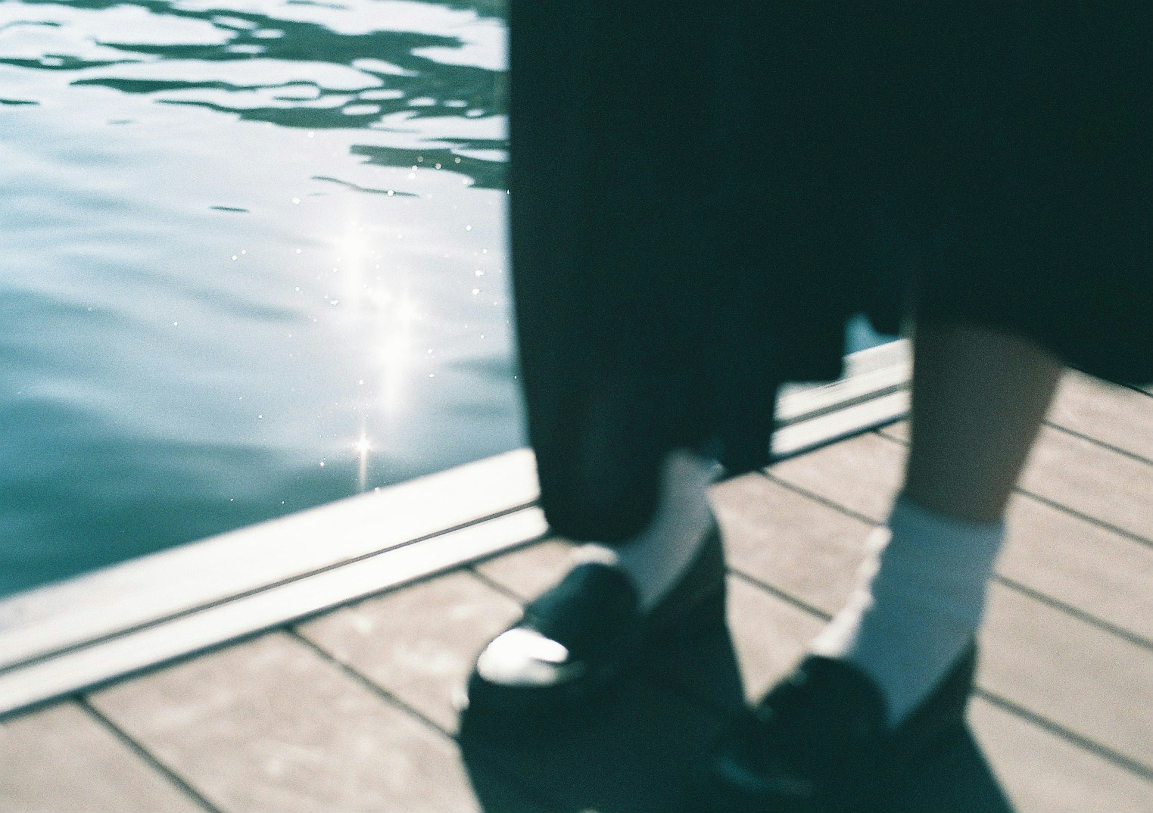 Feet in black shoes and white socks near the water's edge