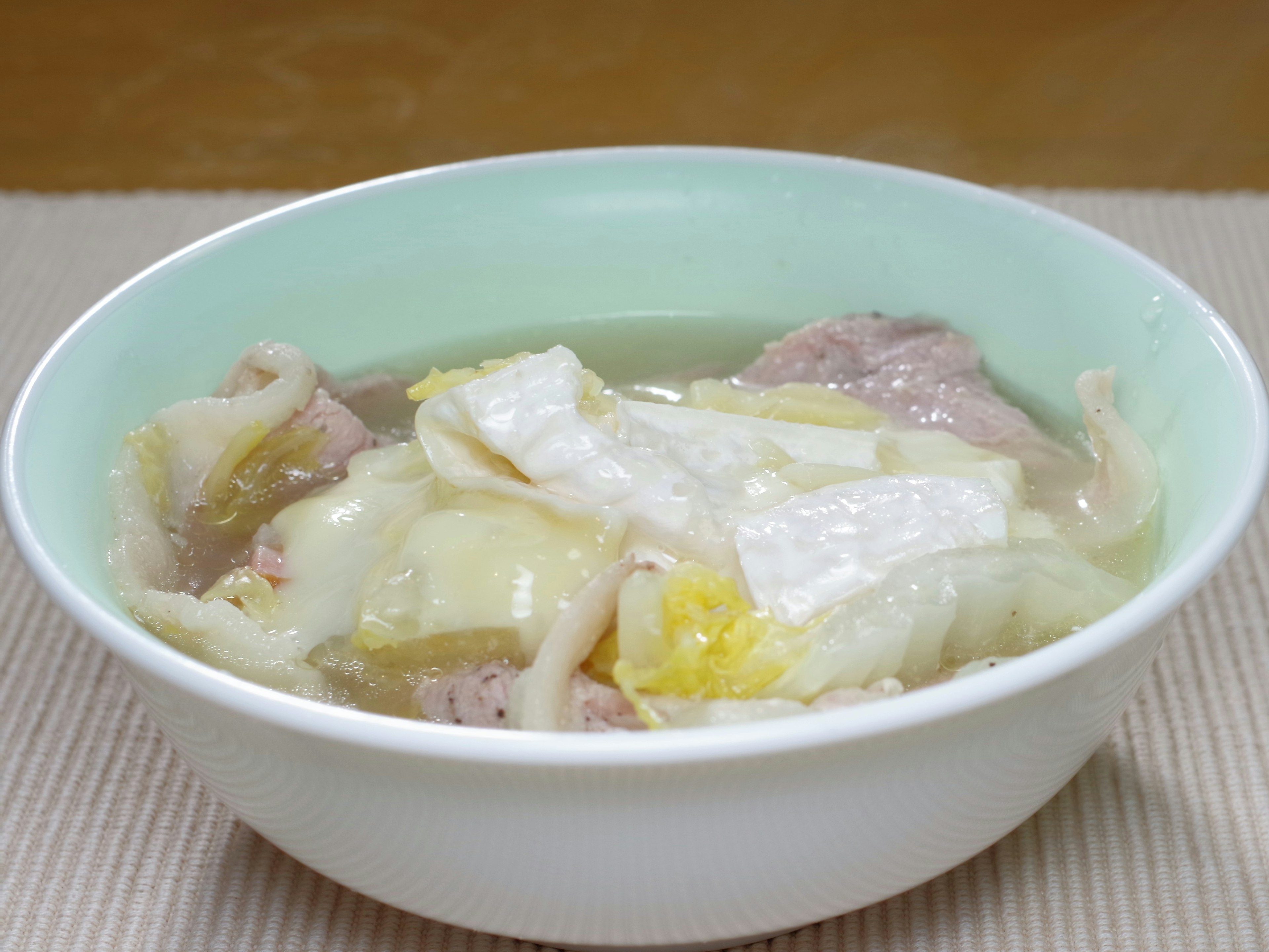 Bowl of clear soup with sliced meat and vegetables