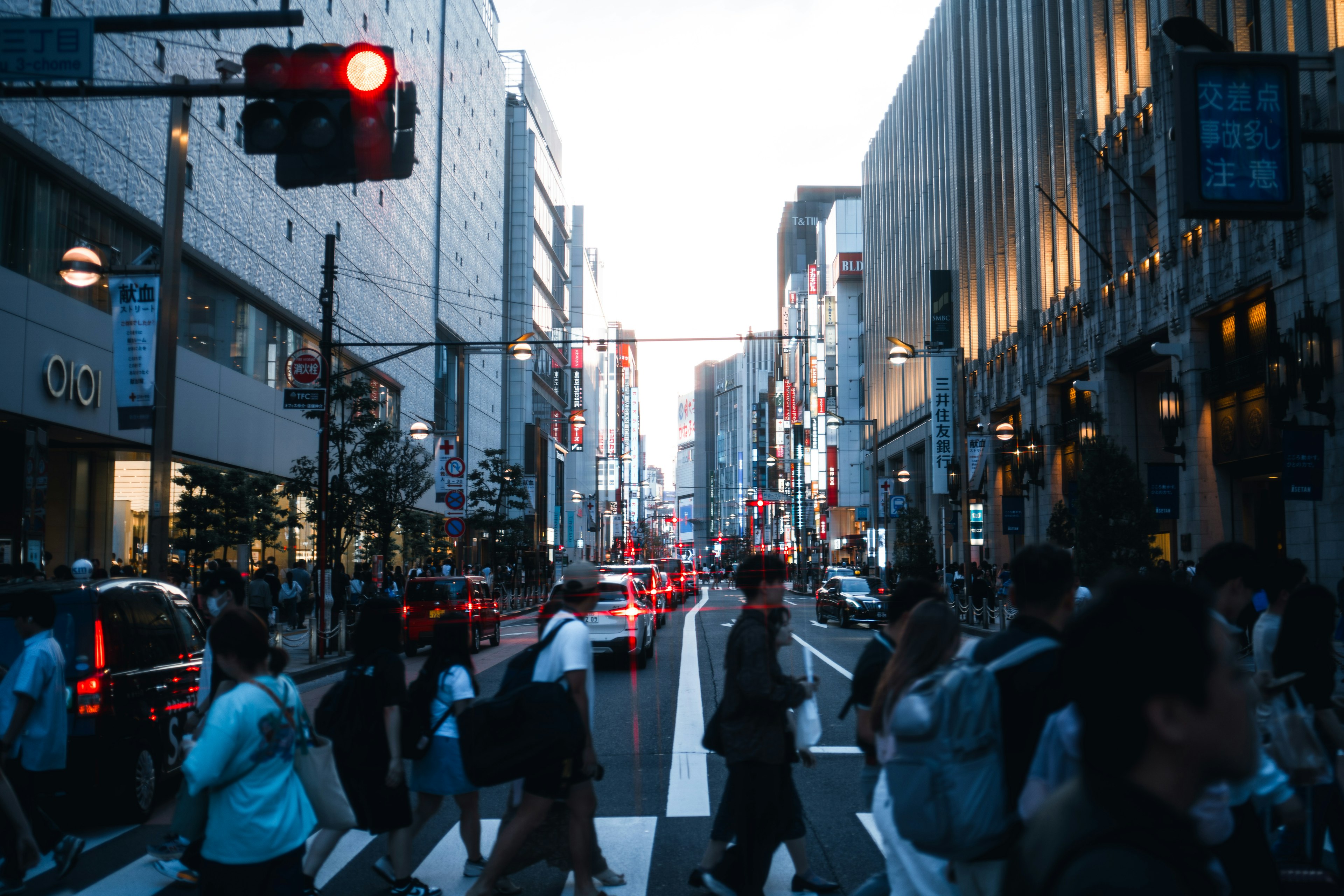 People crossing at a busy intersection under a red traffic light