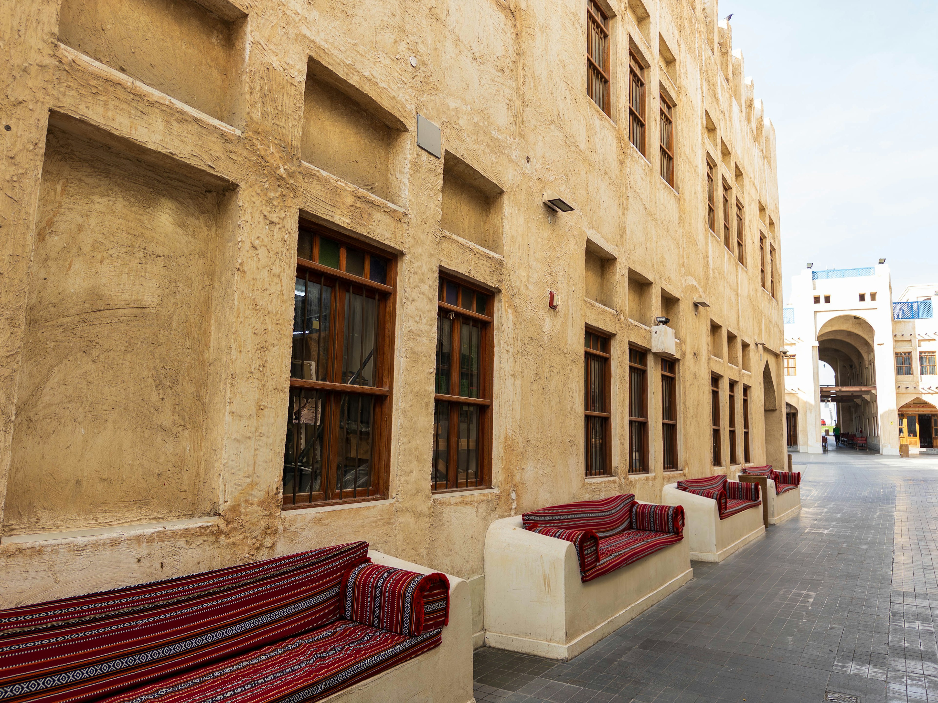 Architecture arabe traditionnelle avec fenêtres et bancs le long de la rue