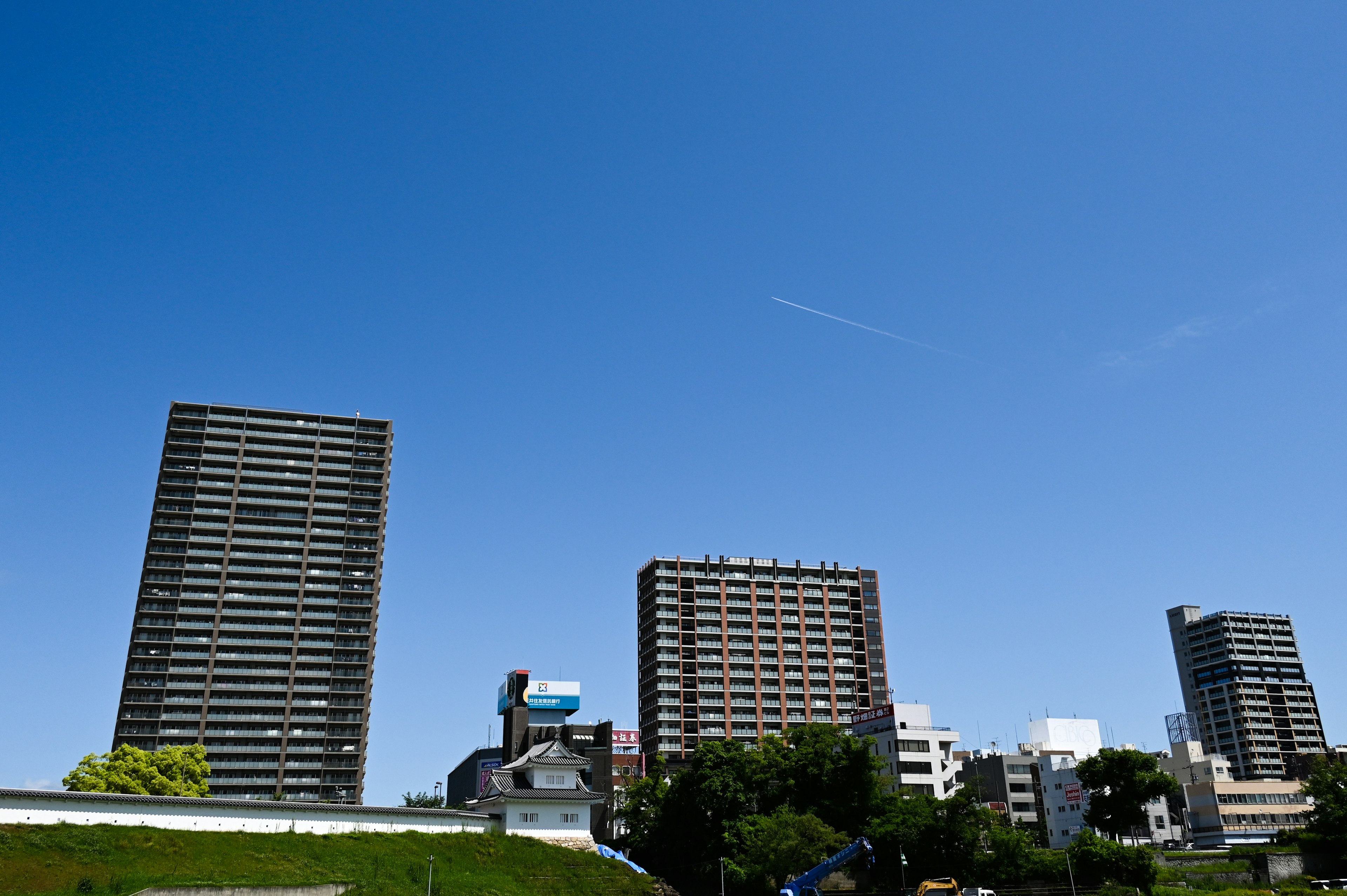 High-rise buildings under a clear blue sky with green grass in the foreground