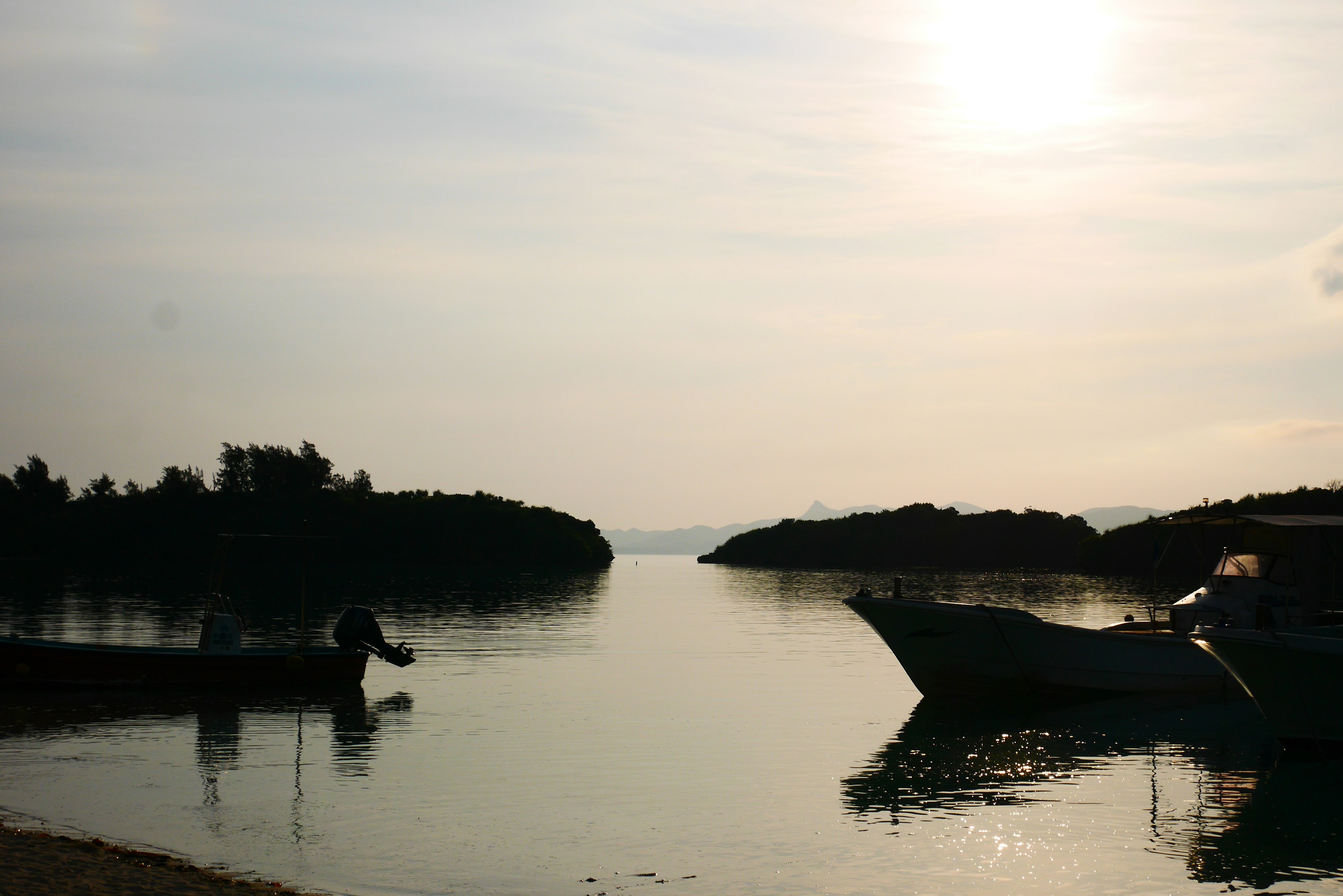 Serene waterfront scene with two boats and a calm sunrise