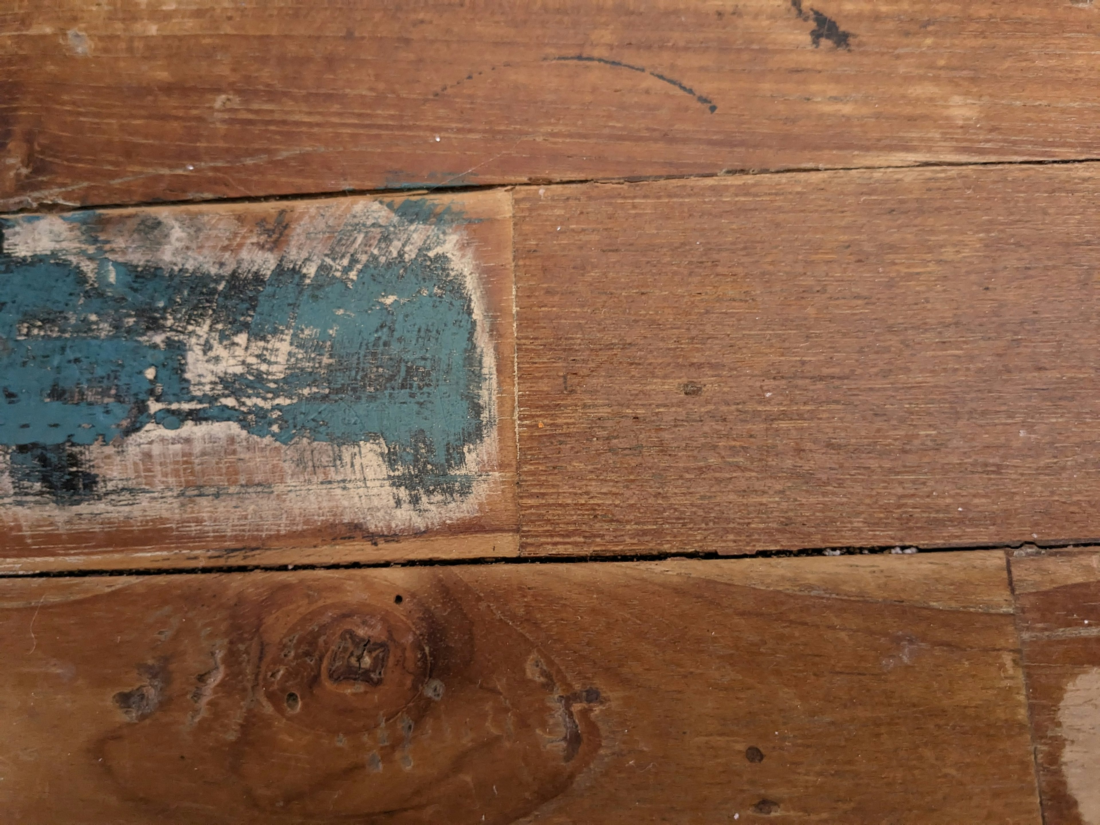 Close-up of wooden floor with blue paint stains and visible grain