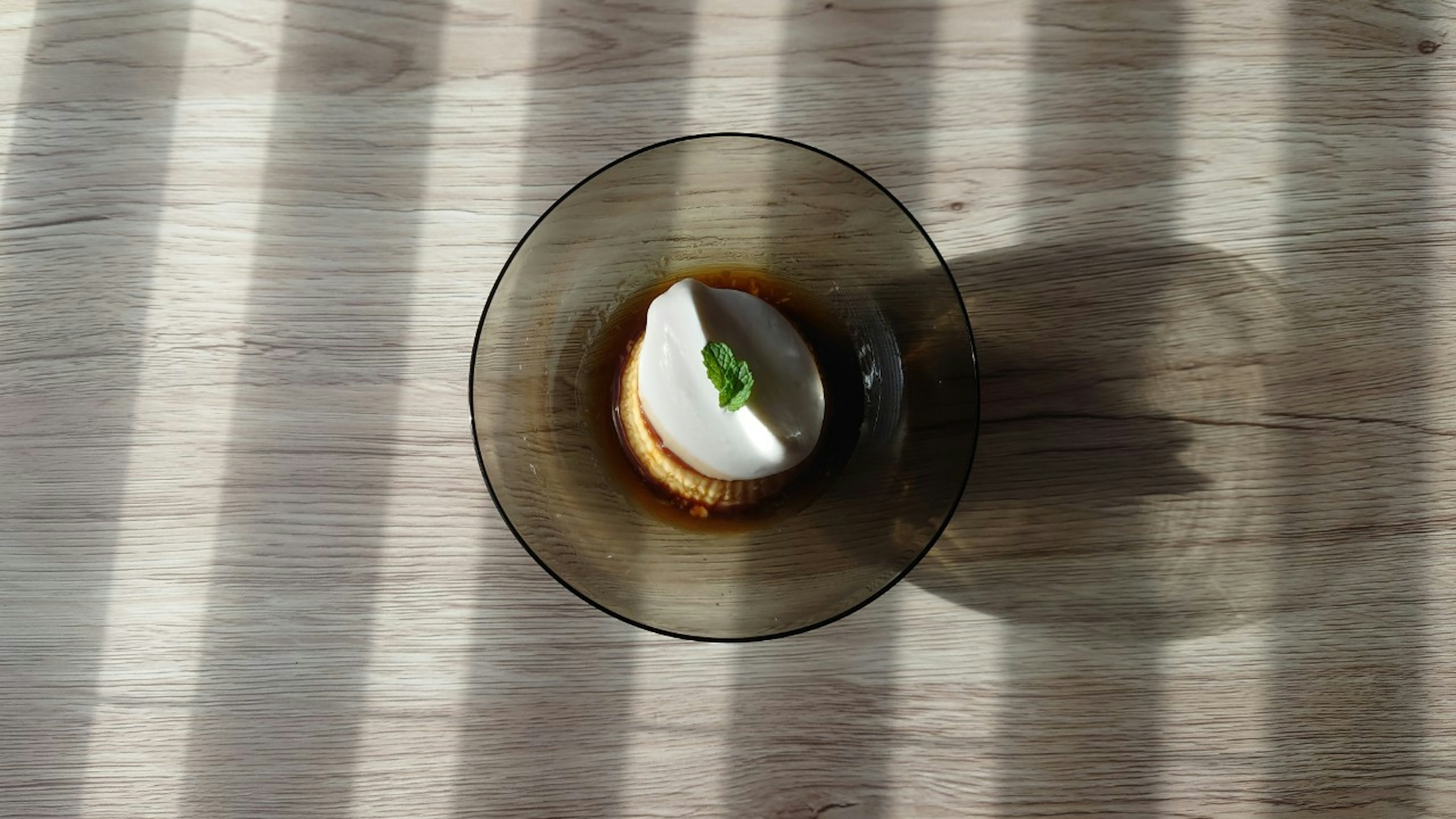 Dessertschale mit Sahnehaube auf einem hellen Holztisch