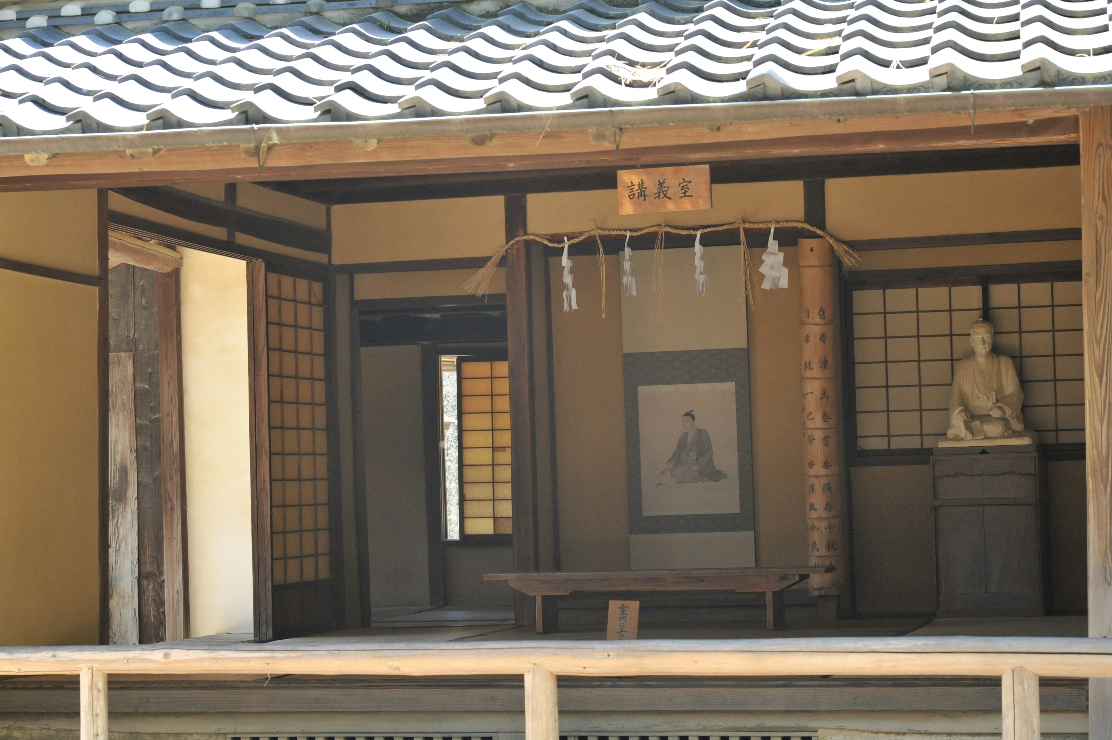 Traditional Japanese house interior featuring a Buddha statue and hanging scroll