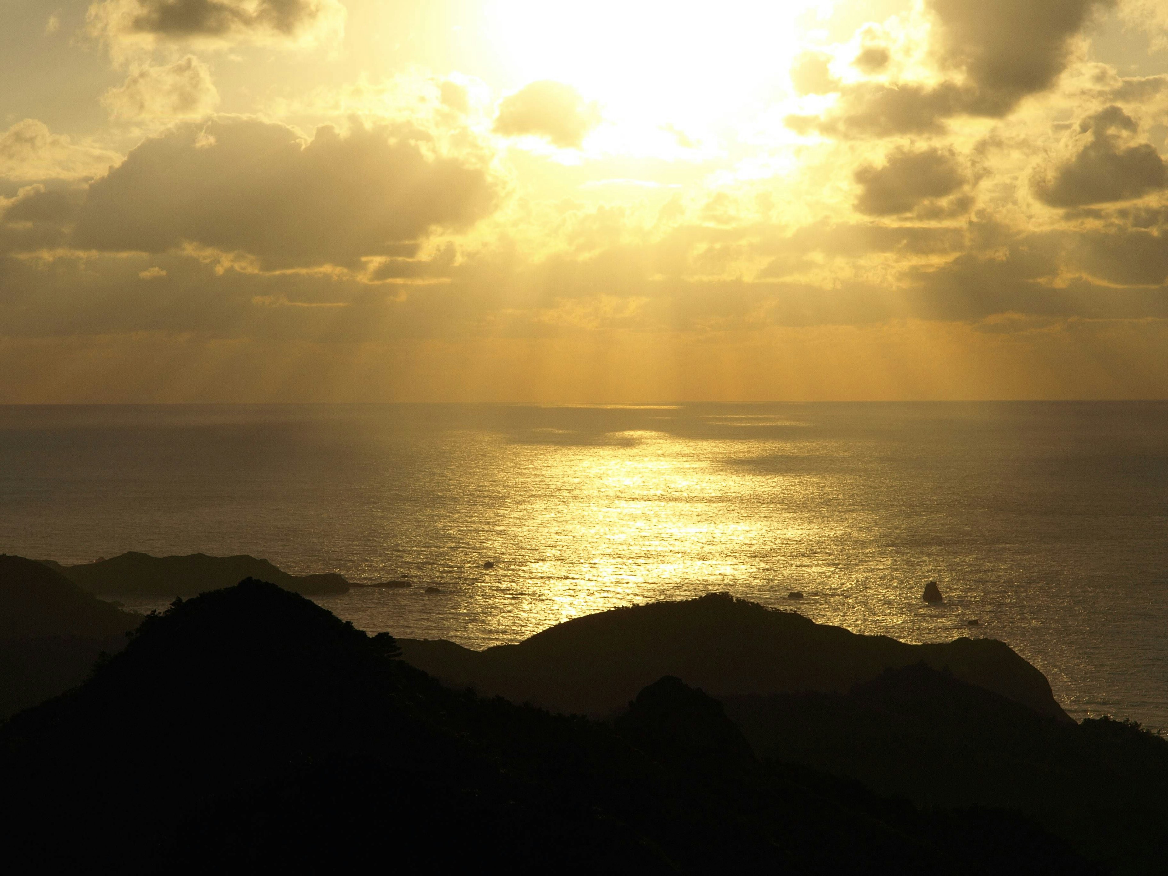 Vista escénica del atardecer reflejándose en el océano con montañas