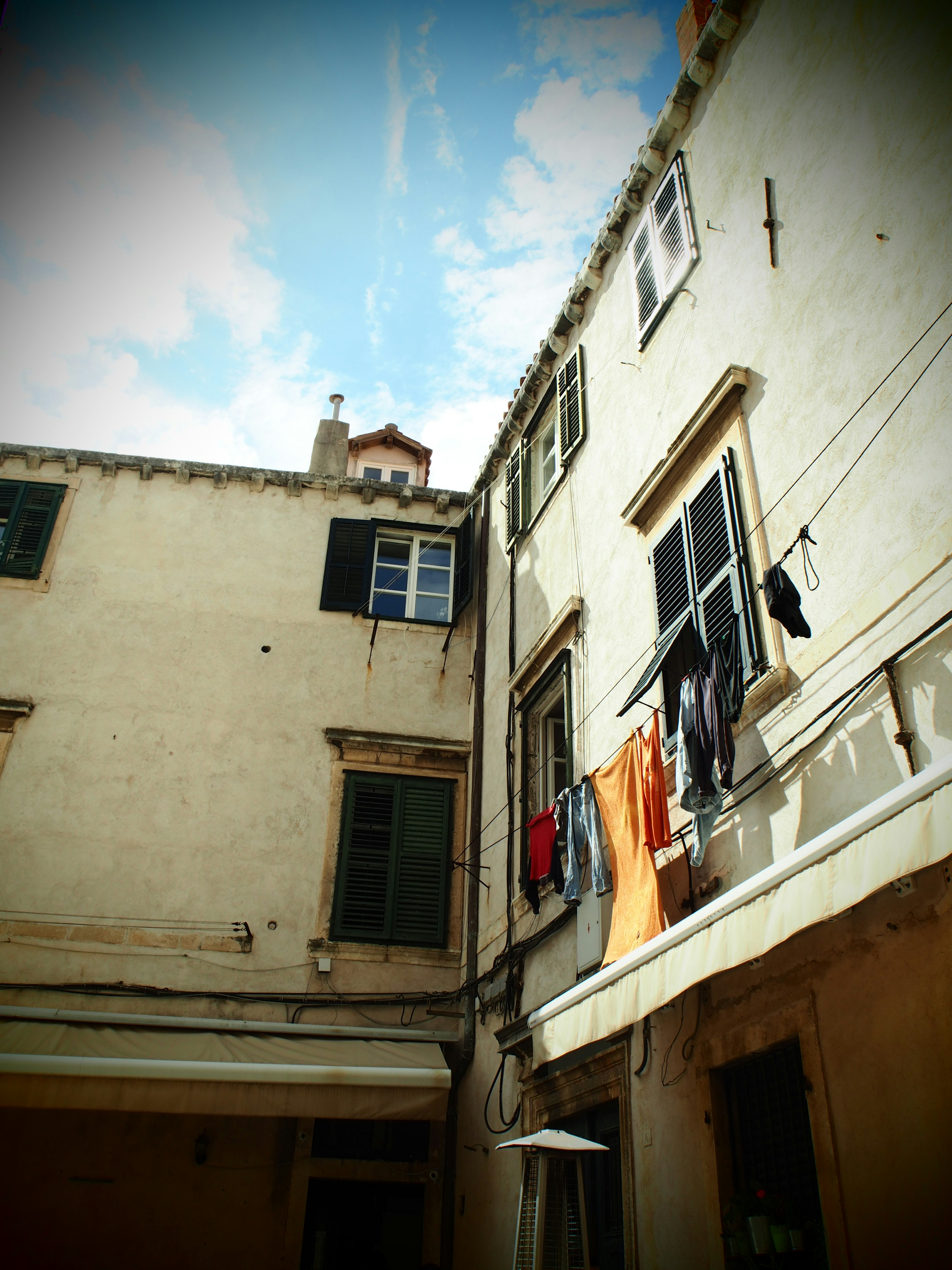 Ancien bâtiment avec du linge suspendu entre les murs sous le ciel bleu